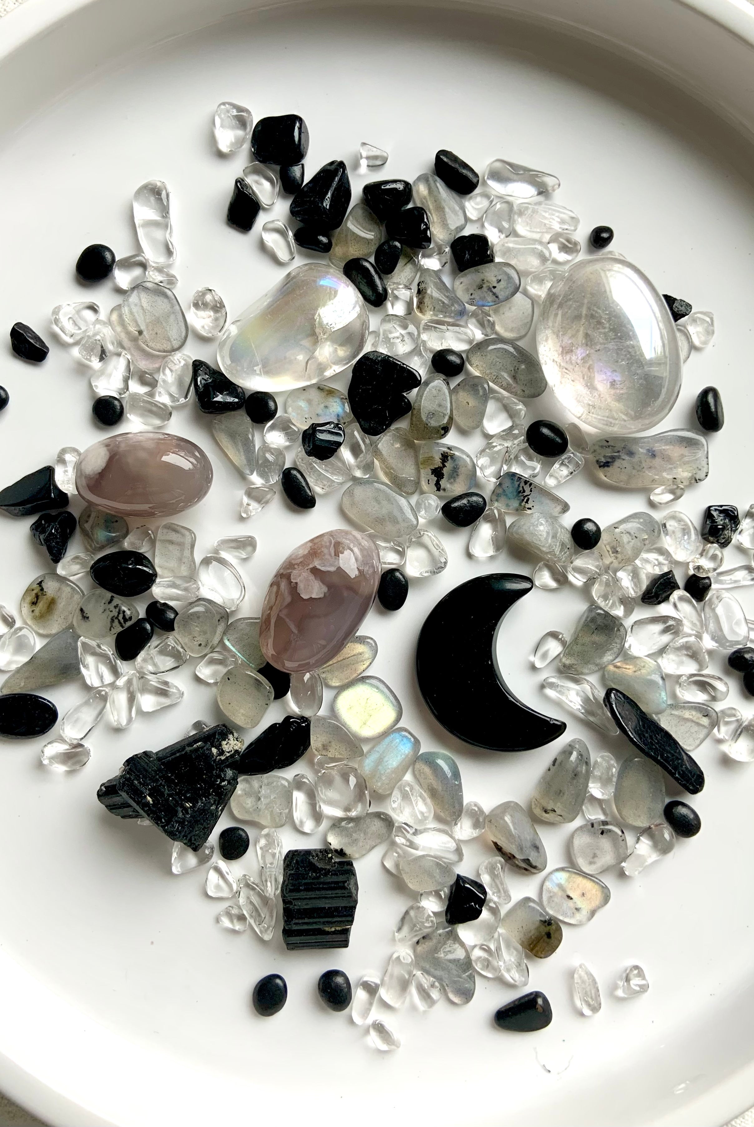 Moon Phase Crystal Confetti blend just a little witchy with a Black Obsidian Crescent Moon Carving. Pic shows the "confetti + tumbles + moon" option spread out on a white plate