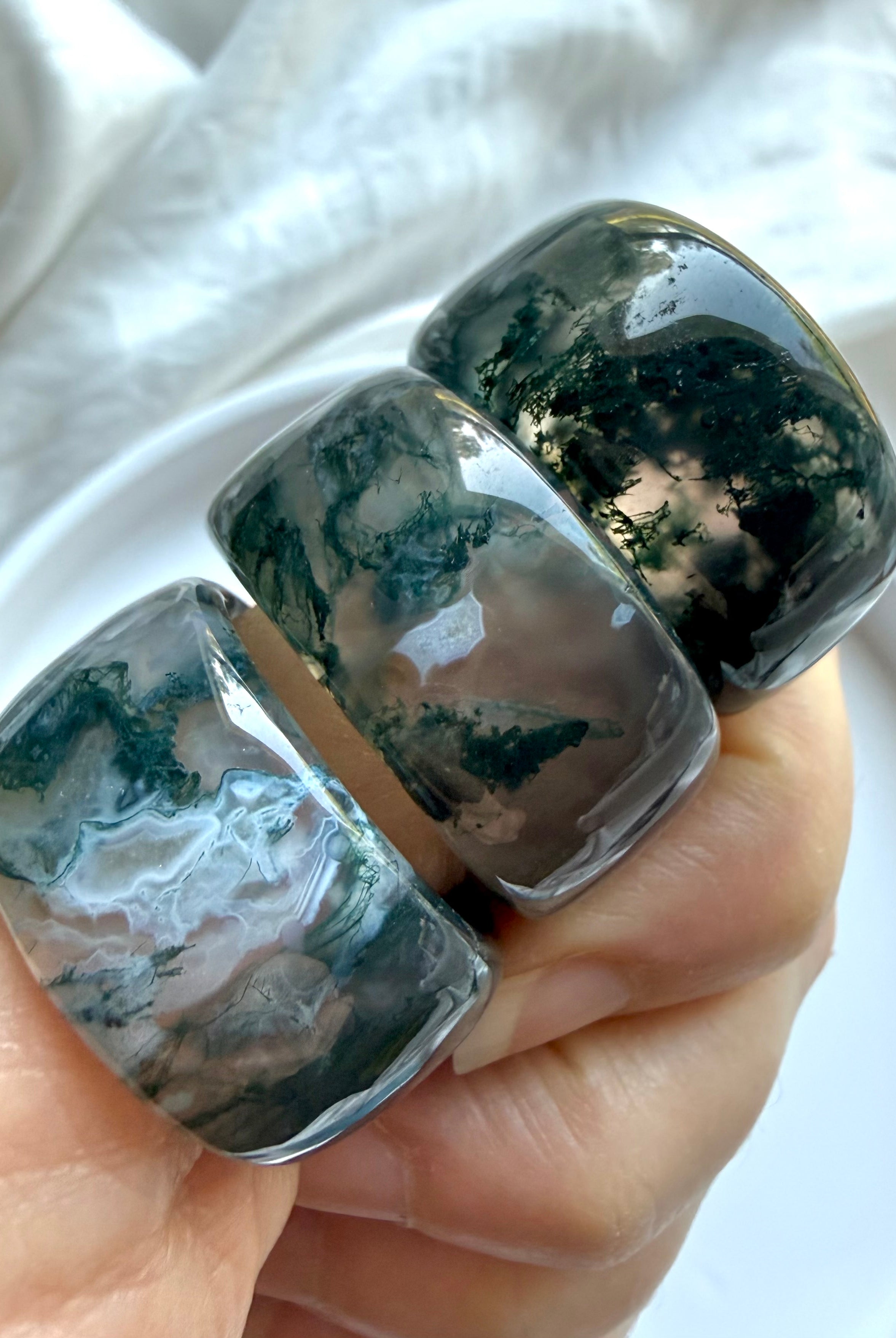 wide moss agate statement rings with translucent scenic inclusions and earthy green landscape patterns on white marble