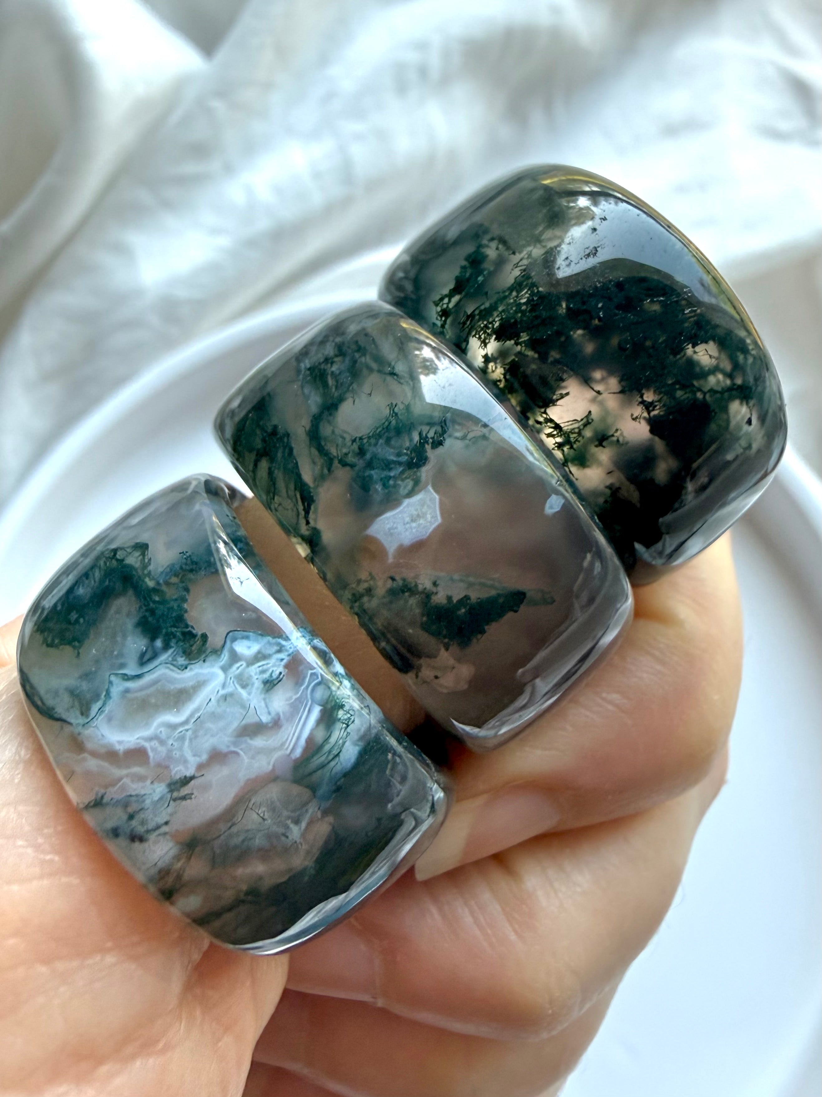 wide moss agate statement rings with translucent scenic inclusions and earthy green landscape patterns on white marble