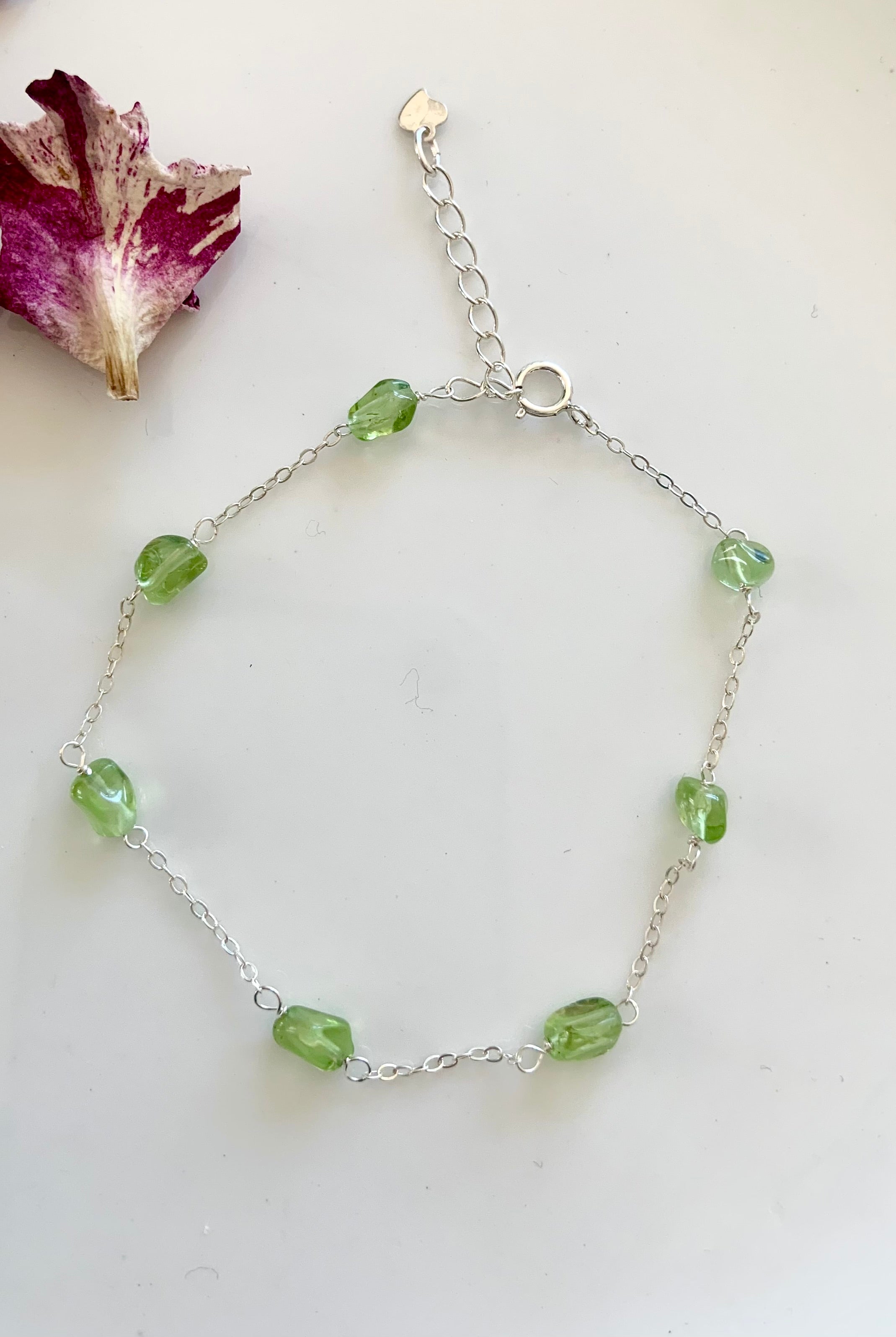 Dainty sterling silver Peridot gemstone bracelet with wrist size extender shown on a white background. Also available in gold filled