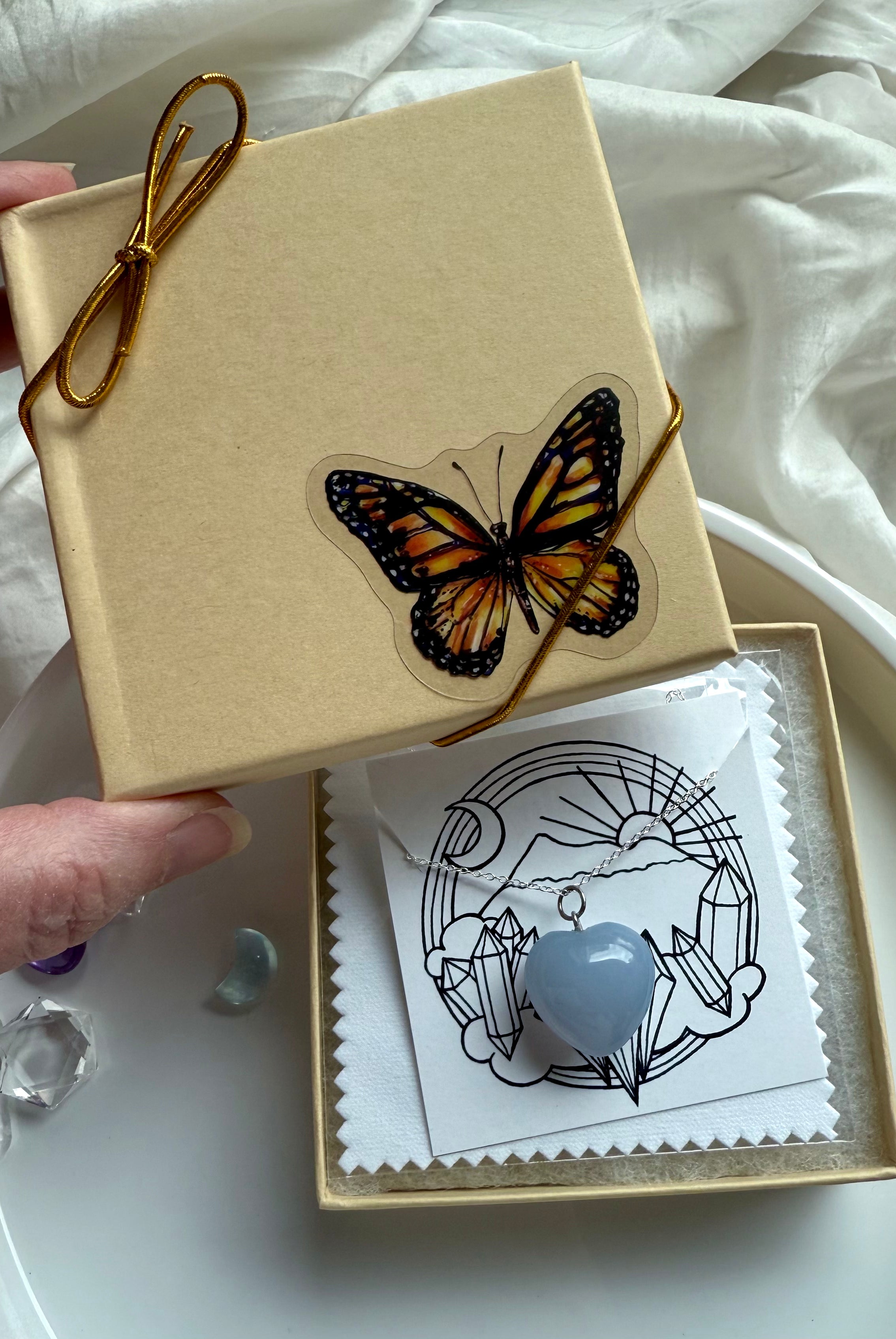 Gift-ready Blue Chalcedony heart pendant necklace in butterfly box with gold cord and crystal-themed packaging.