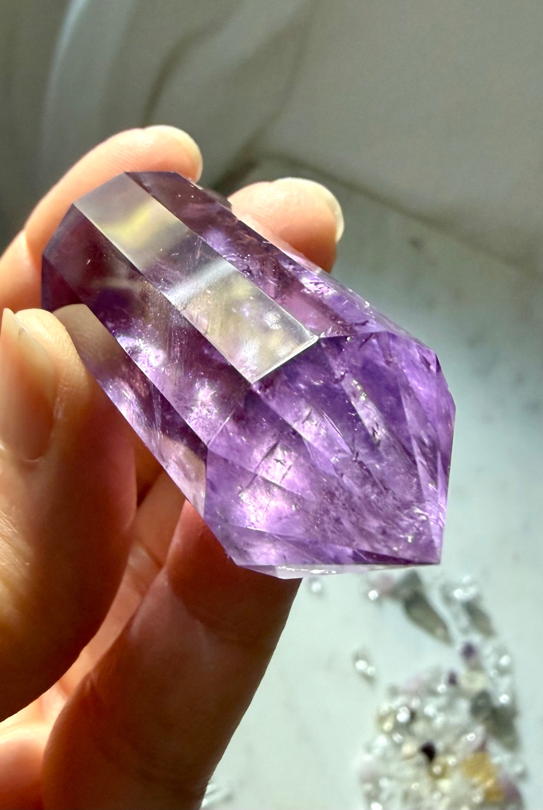 Handheld double terminated Amethyst crystal wand with twelve symmetrical facets and rich purple color
