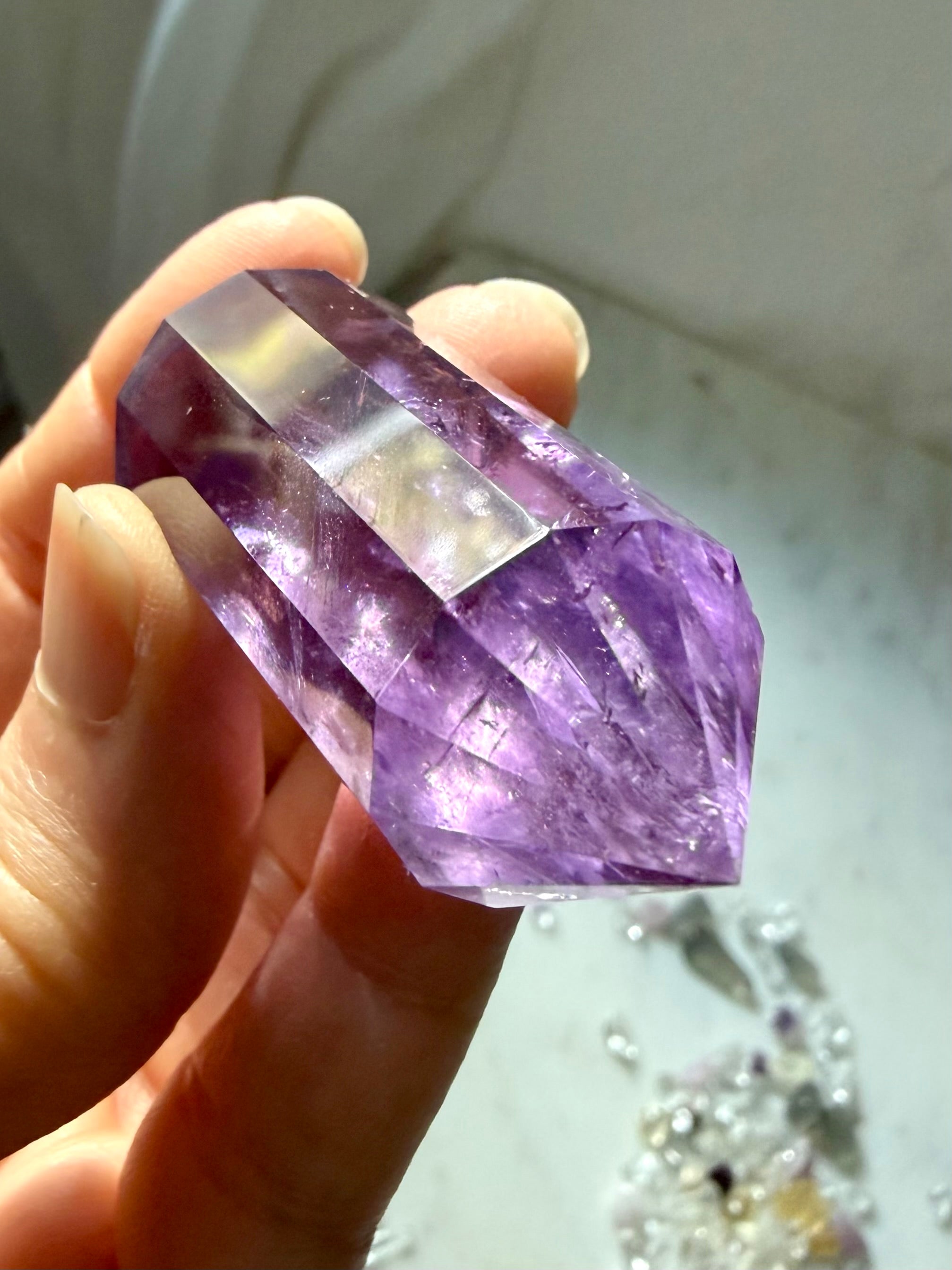 Handheld double terminated Amethyst crystal wand with twelve symmetrical facets and rich purple color