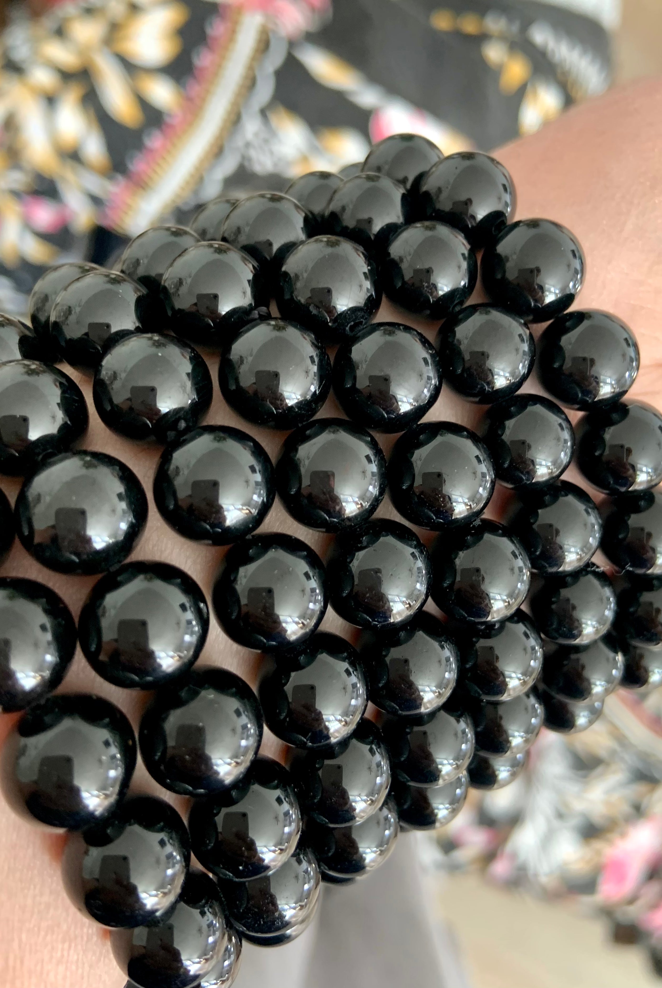 Angled closeup of stacked glossy Black Tourmaline bracelets — natural black crystal beads for protection, clearing, and grounding