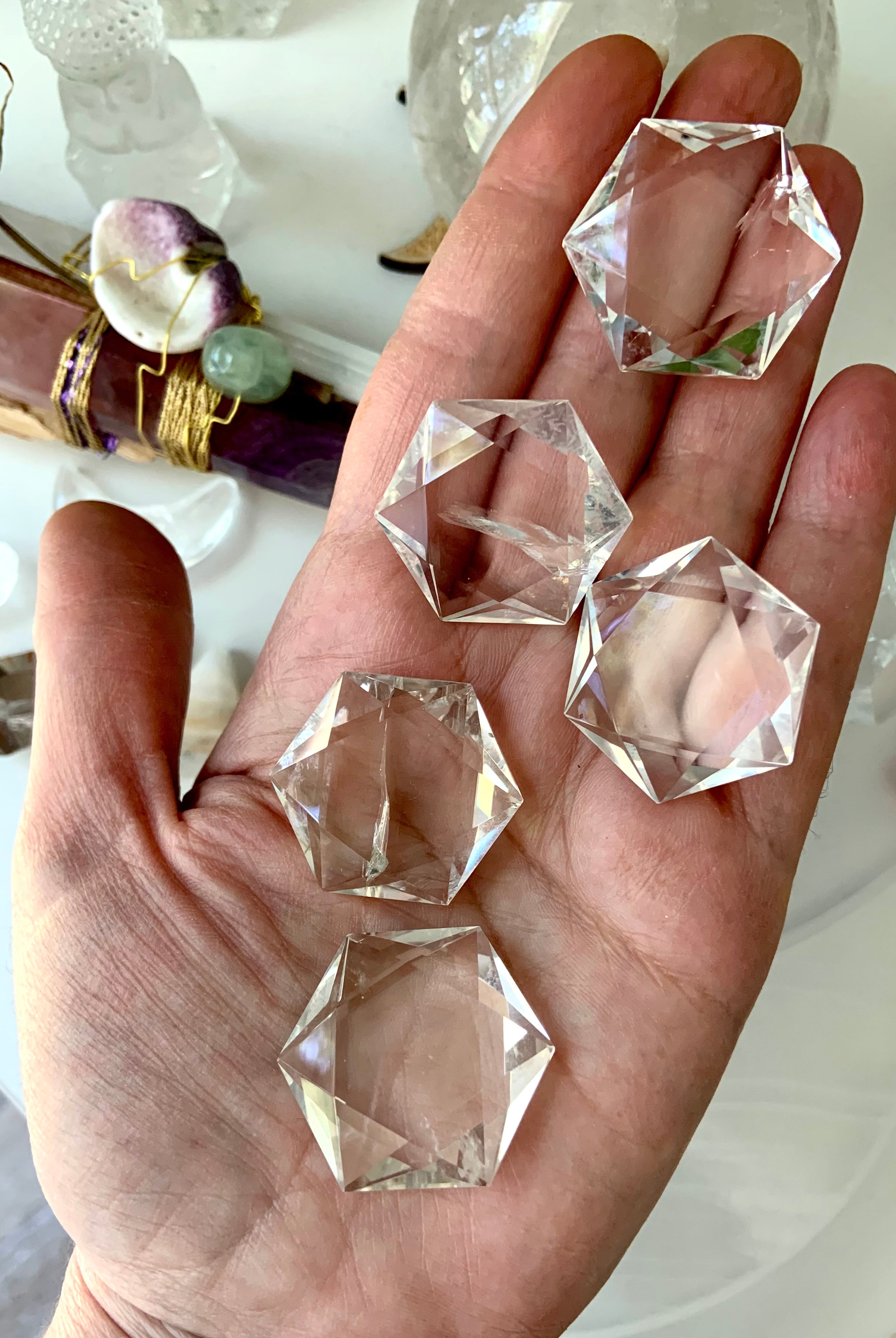 Array of faceted Clear Quartz hexagon crystals displayed on hand, sparkling with prismatic clarity