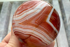A stunning banded carnelian sphere with an intricate chevron pattern