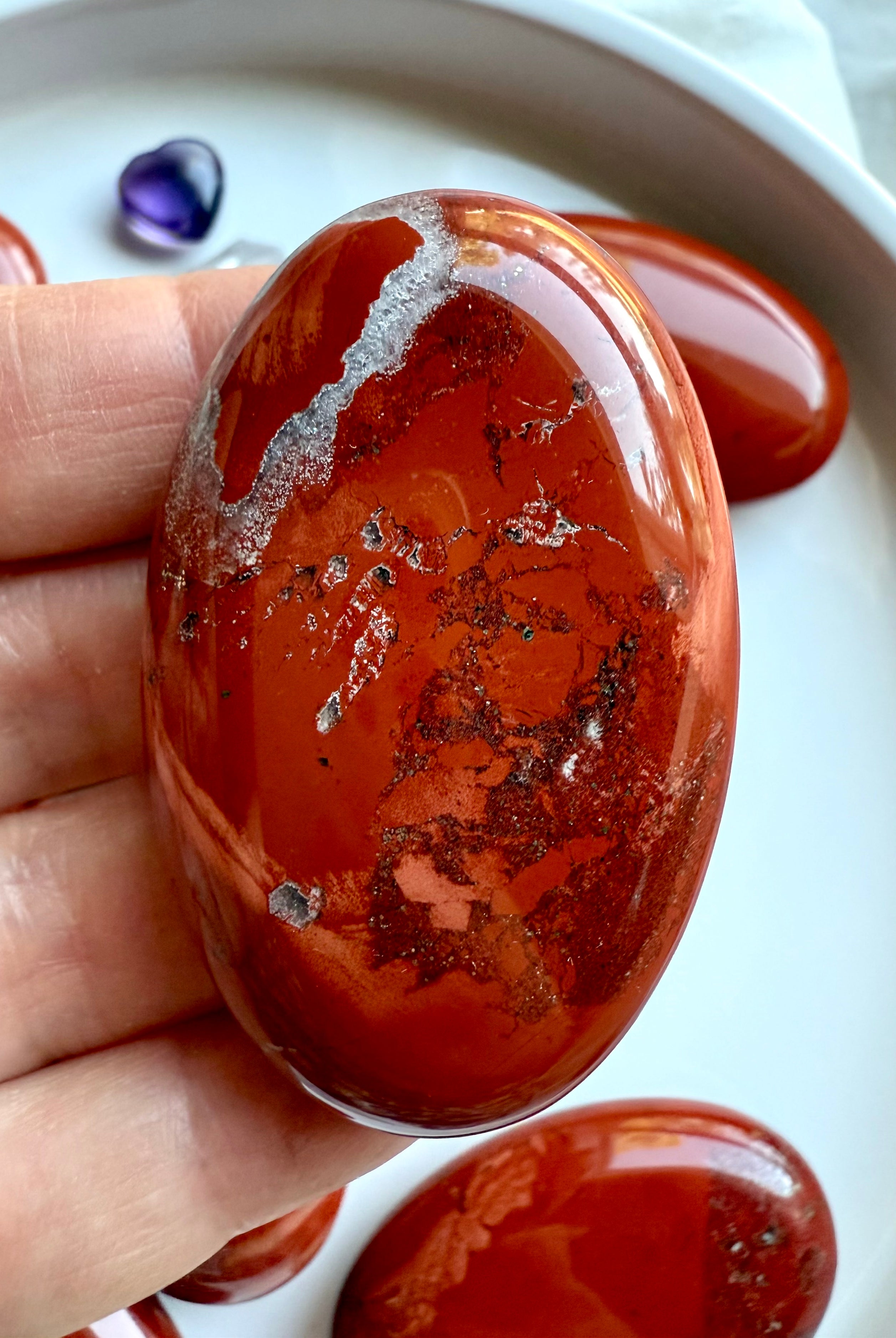Close-up of polished Red Jasper palm stone — grounding crystal for Root Chakra healing and stability.