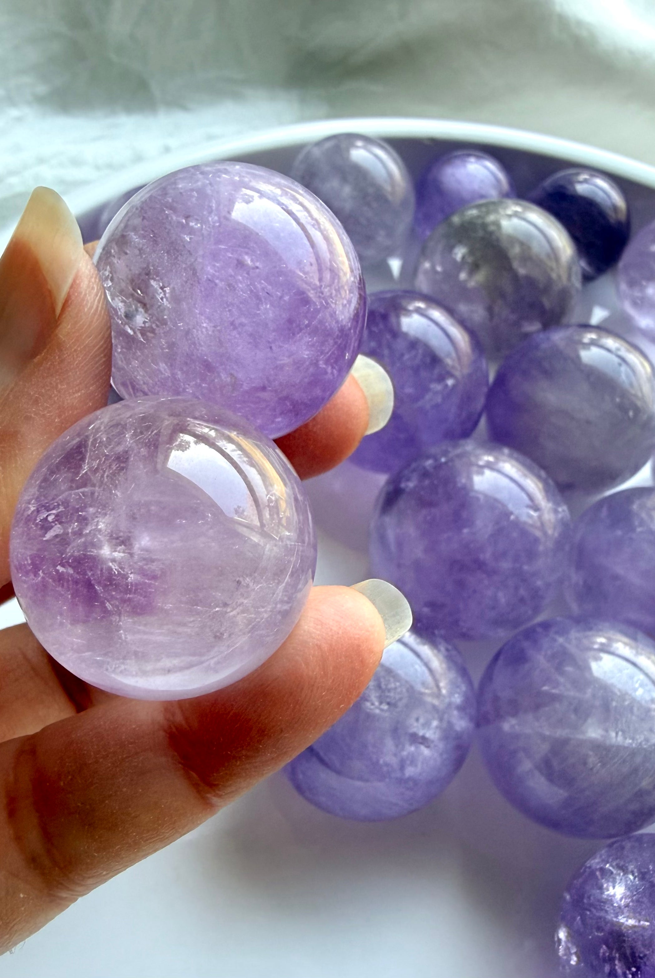 closeup of two polished mini amethyst spheres with smoky quartz inclusions and glassy shine