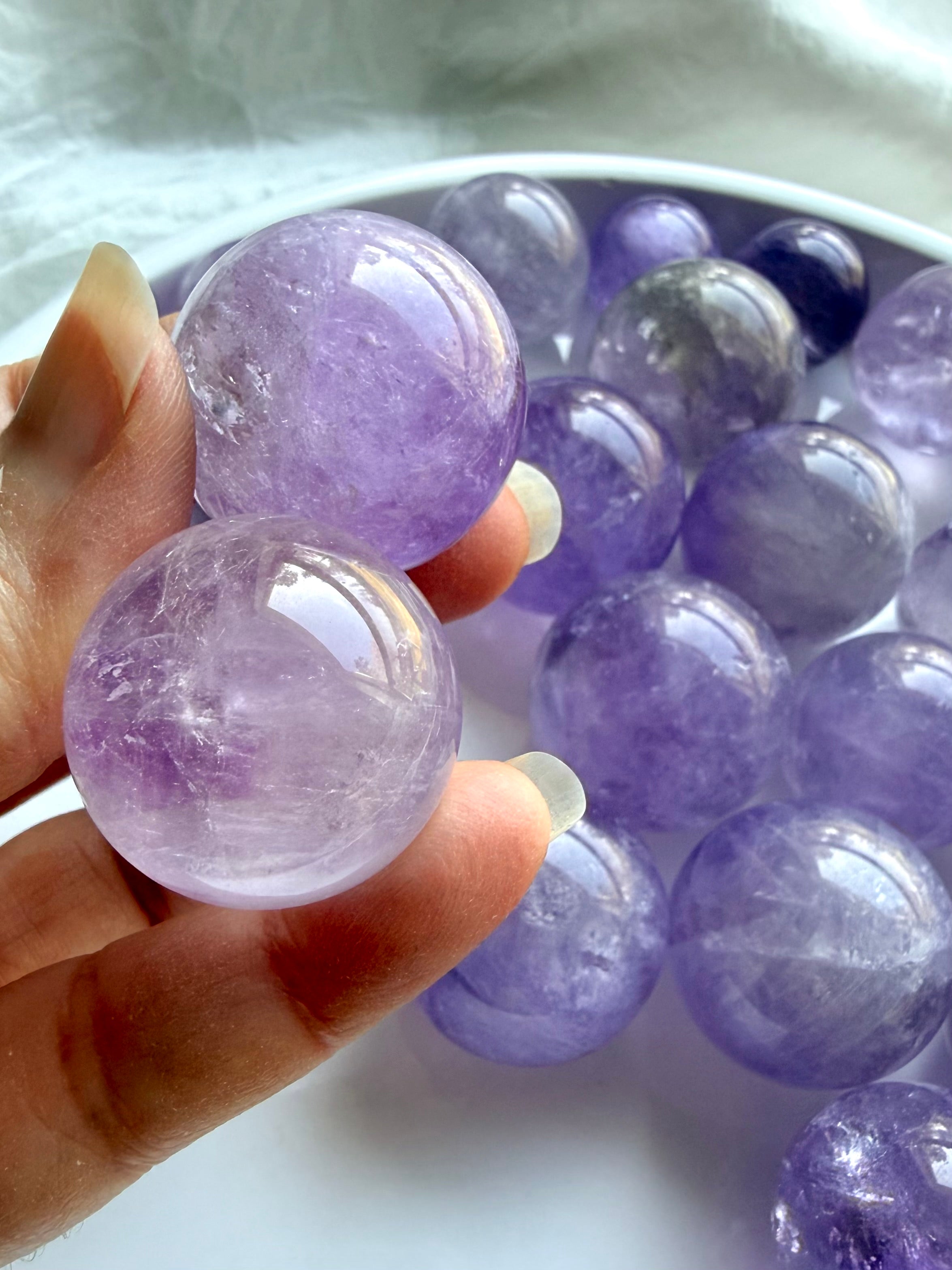 closeup of two polished mini amethyst spheres with smoky quartz inclusions and glassy shine