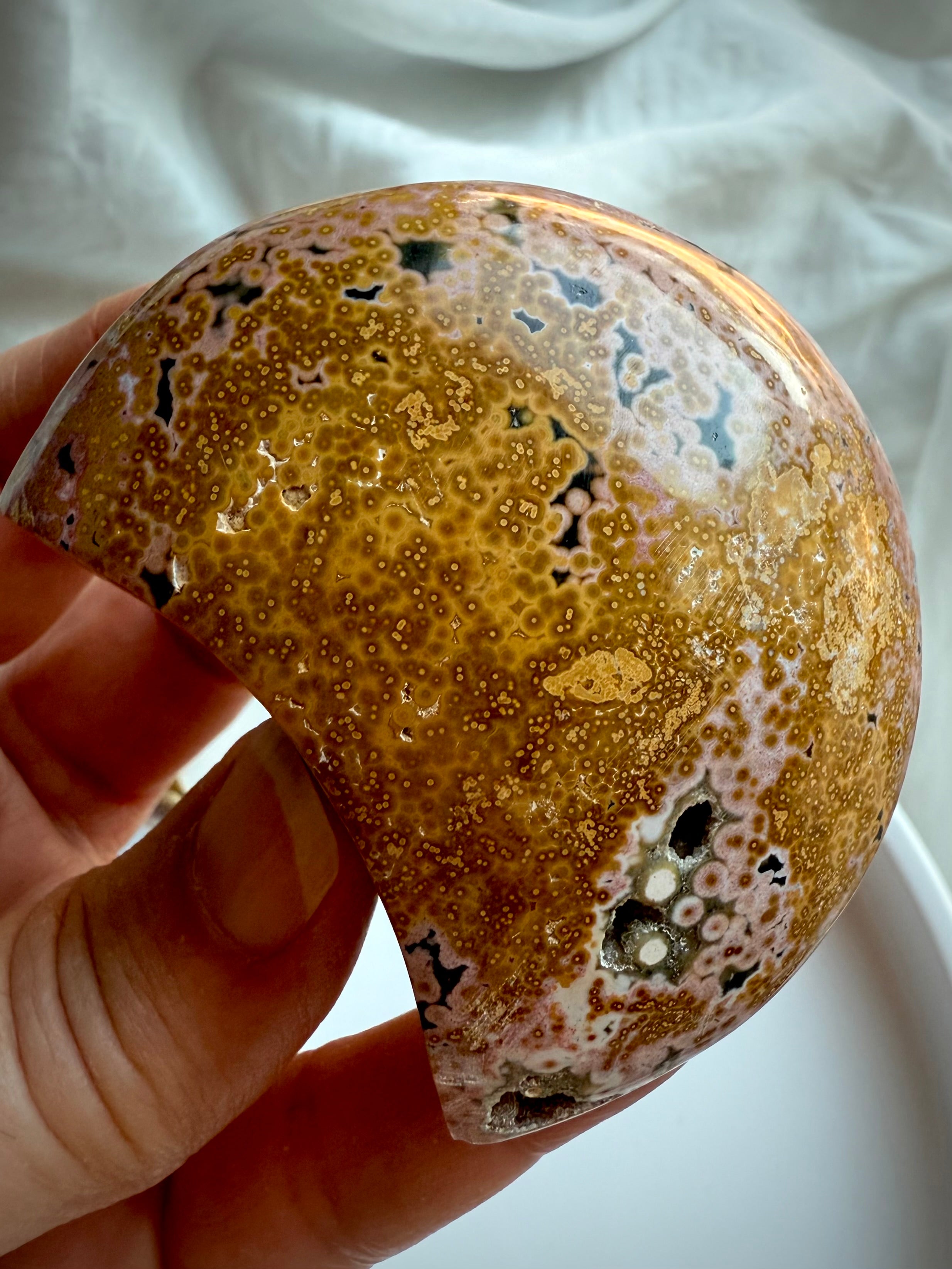 Golden yellow and peach Ocean Jasper moon with intricate orbicular texture and natural vugs held in hand