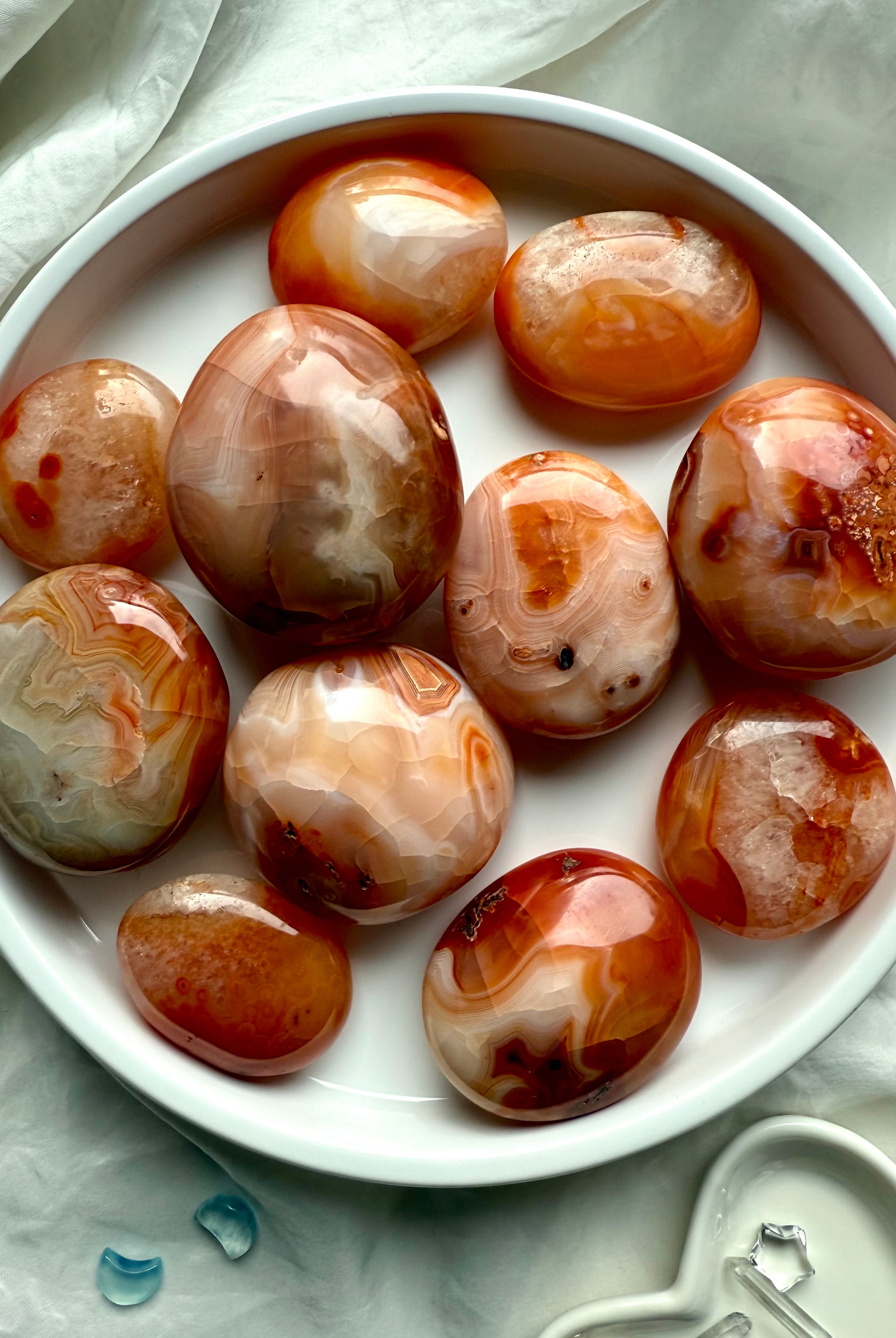 Polished Carnelian palm stones in a white dish — grounding crystals for vitality, motivation + sacral chakra healing