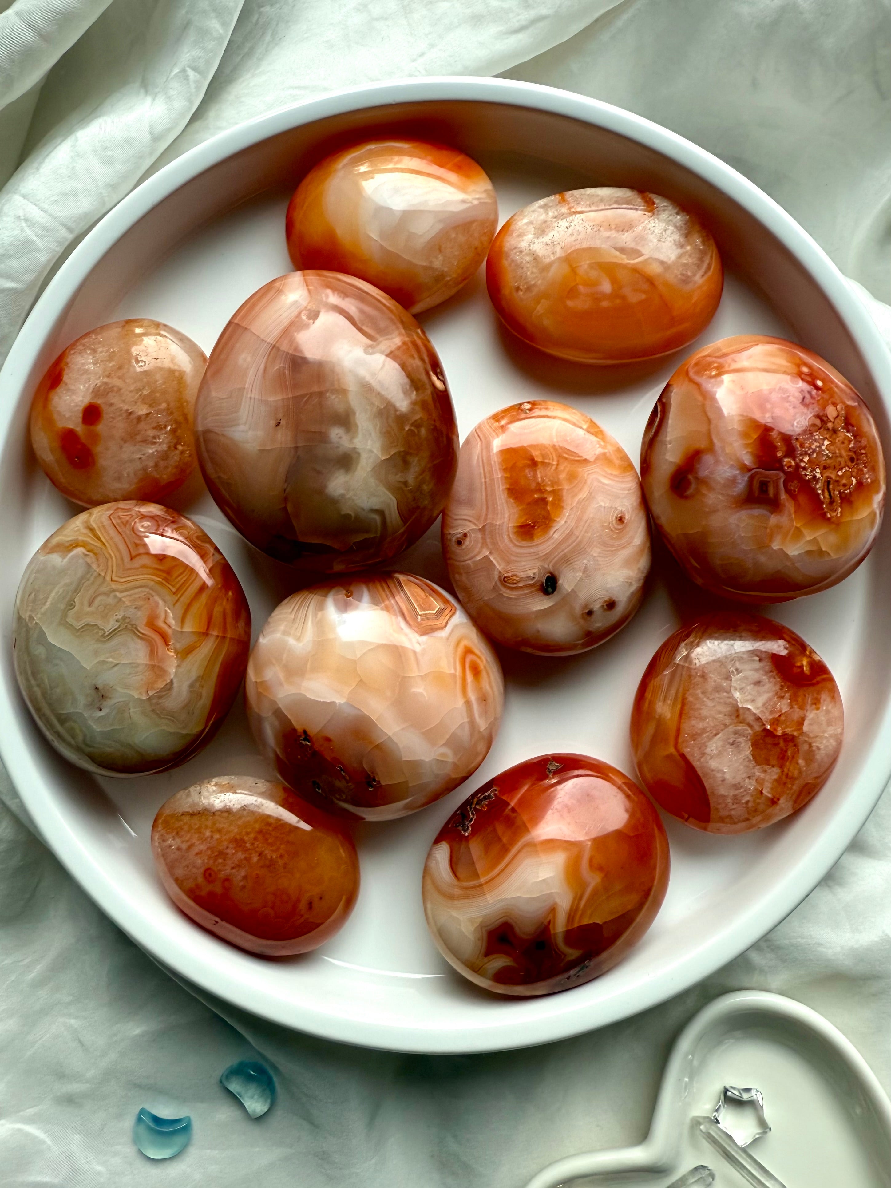 Polished Carnelian palm stones in a white dish — grounding crystals for vitality, motivation + sacral chakra healing