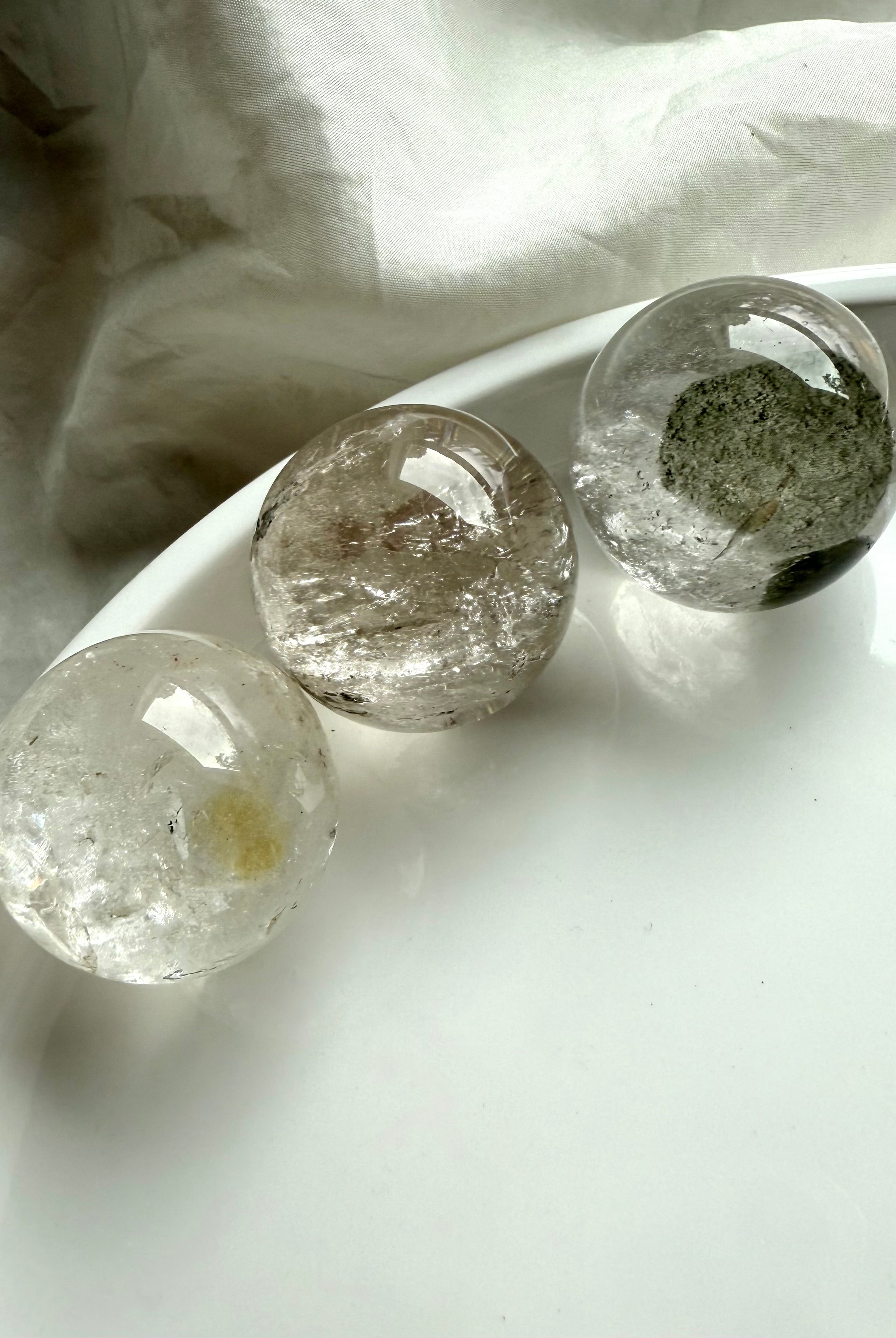 three garden quartz spheres on a white plate – lodolite spheres for spiritual healing