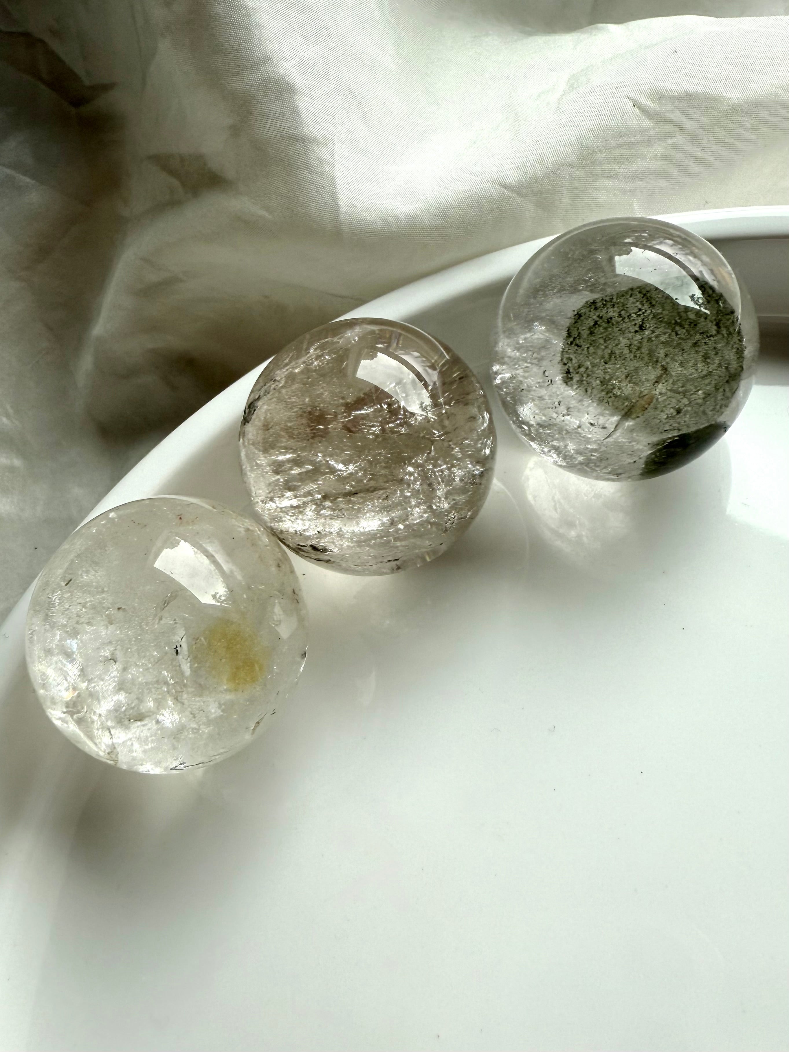 three garden quartz spheres on a white plate – lodolite spheres for spiritual healing