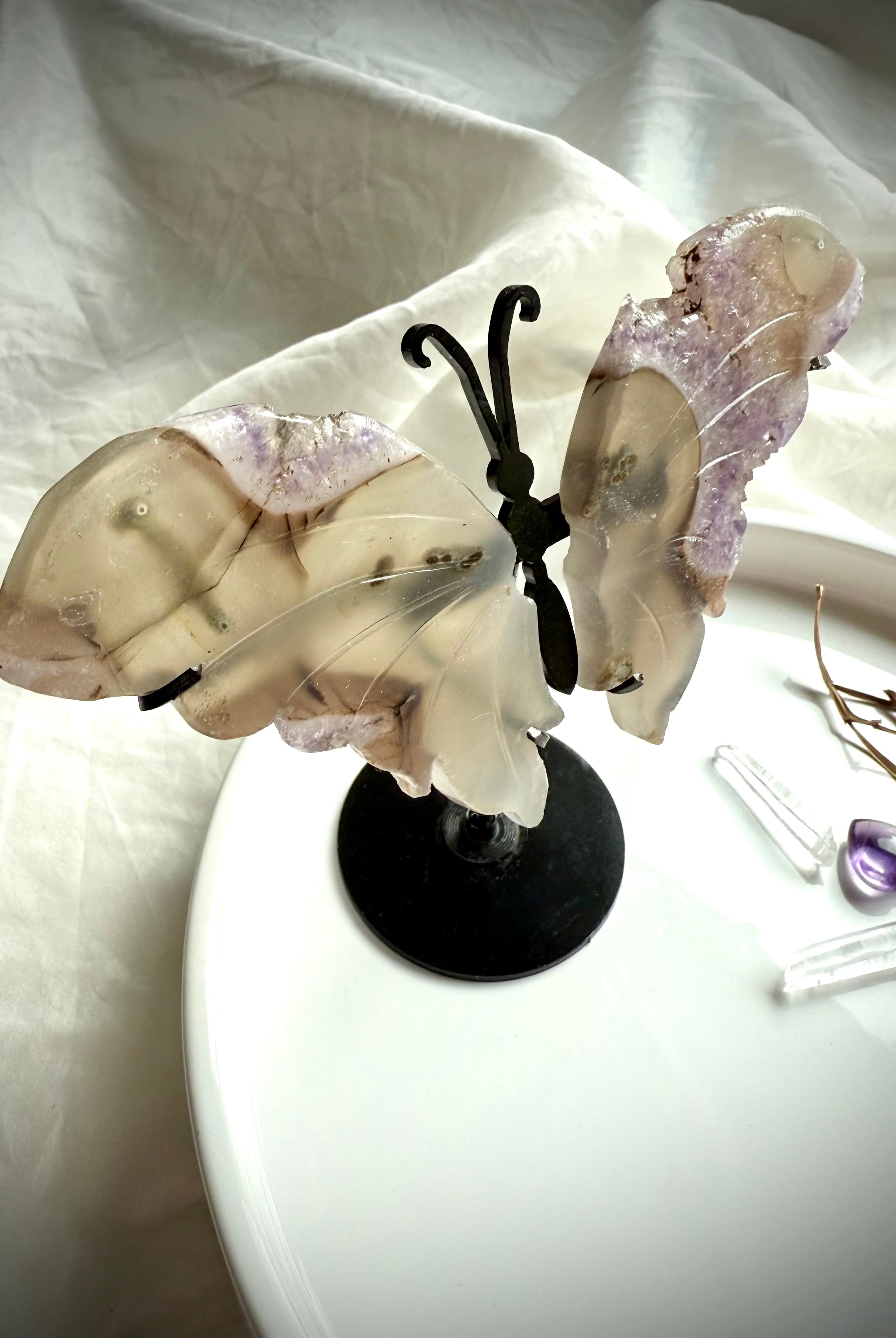 Agate and amethyst druzy butterfly sculpture on metal stand, shown with quartz points and dried flowers for scale.
