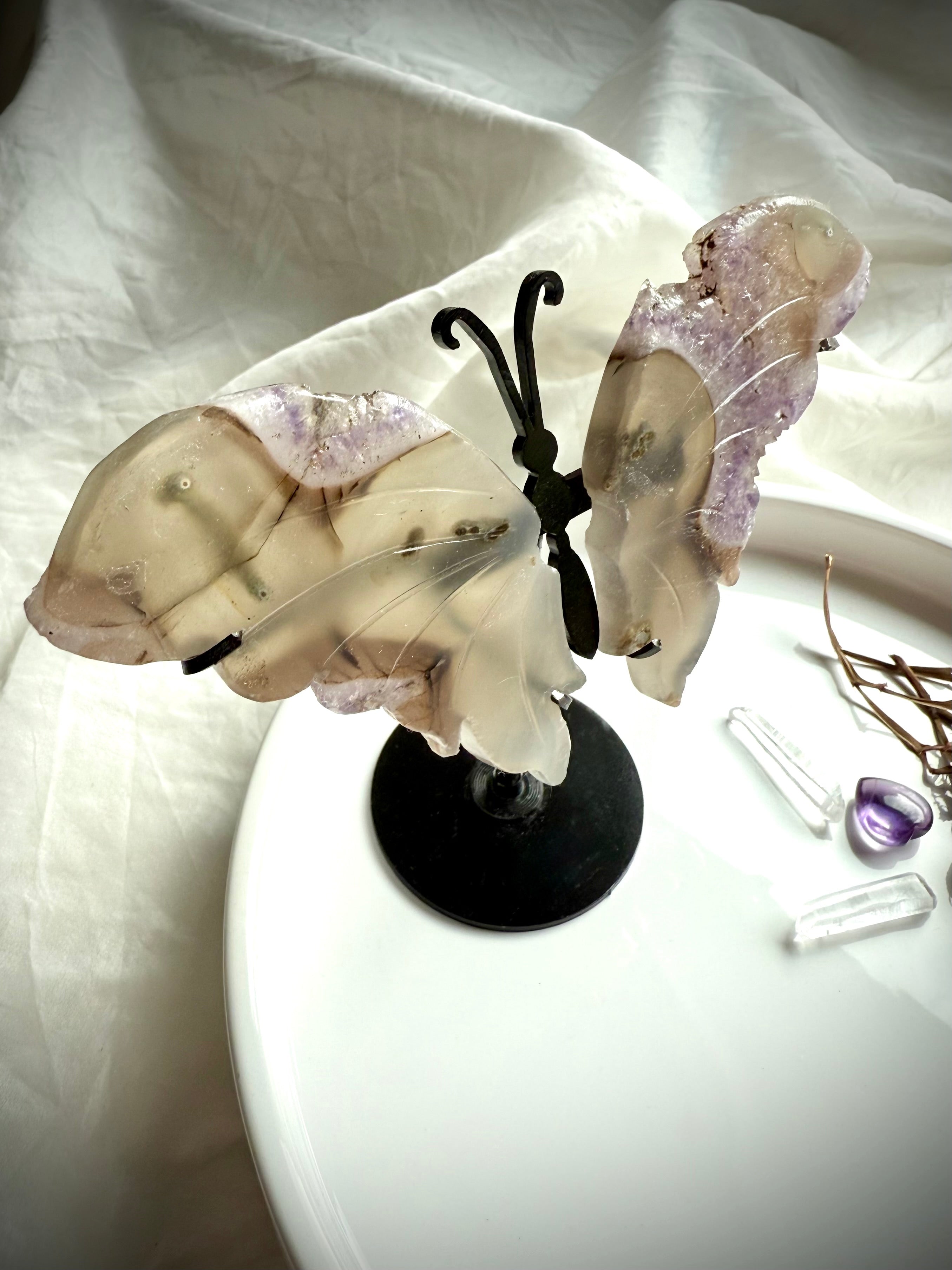 Agate and amethyst druzy butterfly sculpture on metal stand, shown with quartz points and dried flowers for scale.