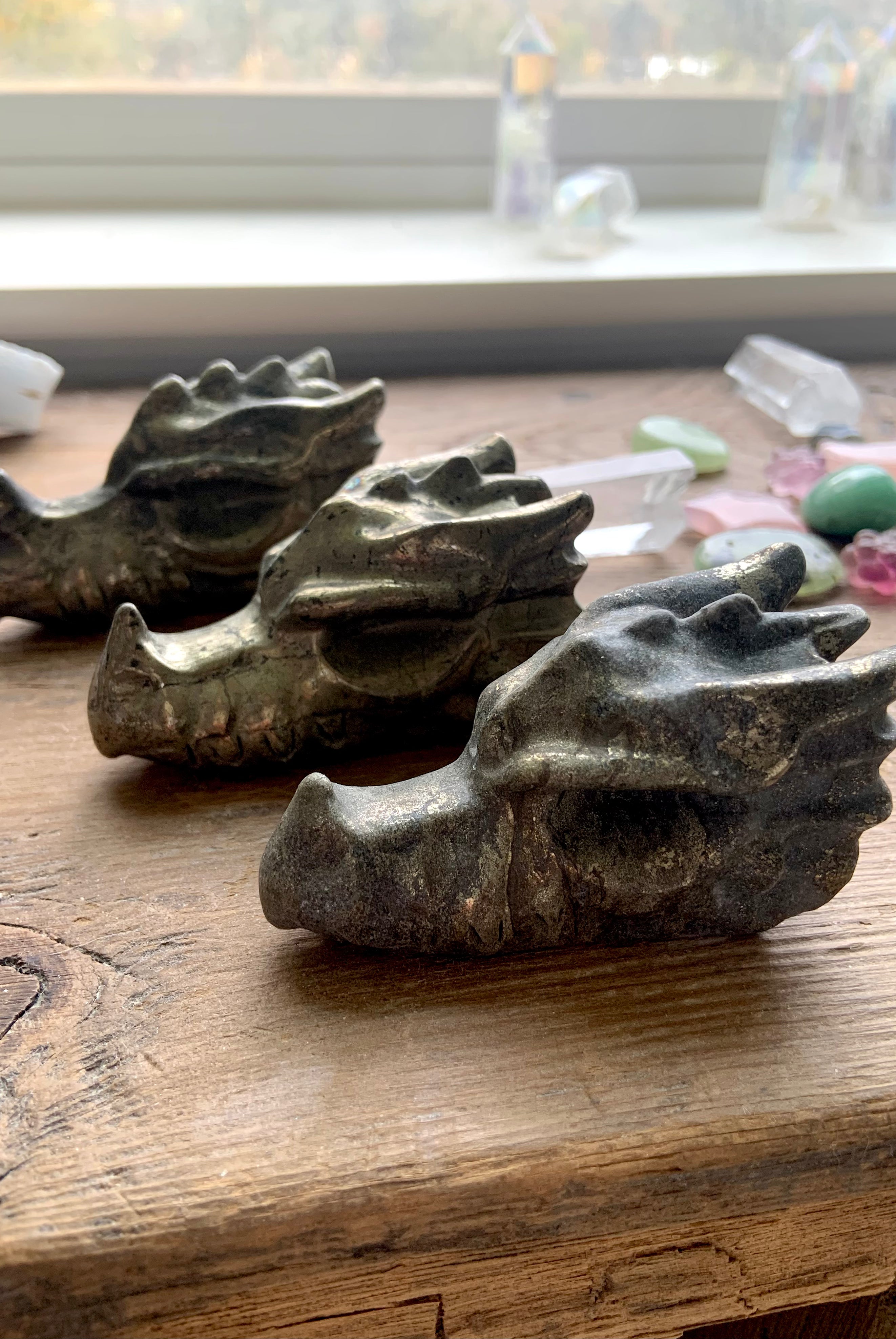 Pyrite crystal dragon carvings styled with clear quartz and rose quartz on wooden altar for energy protection