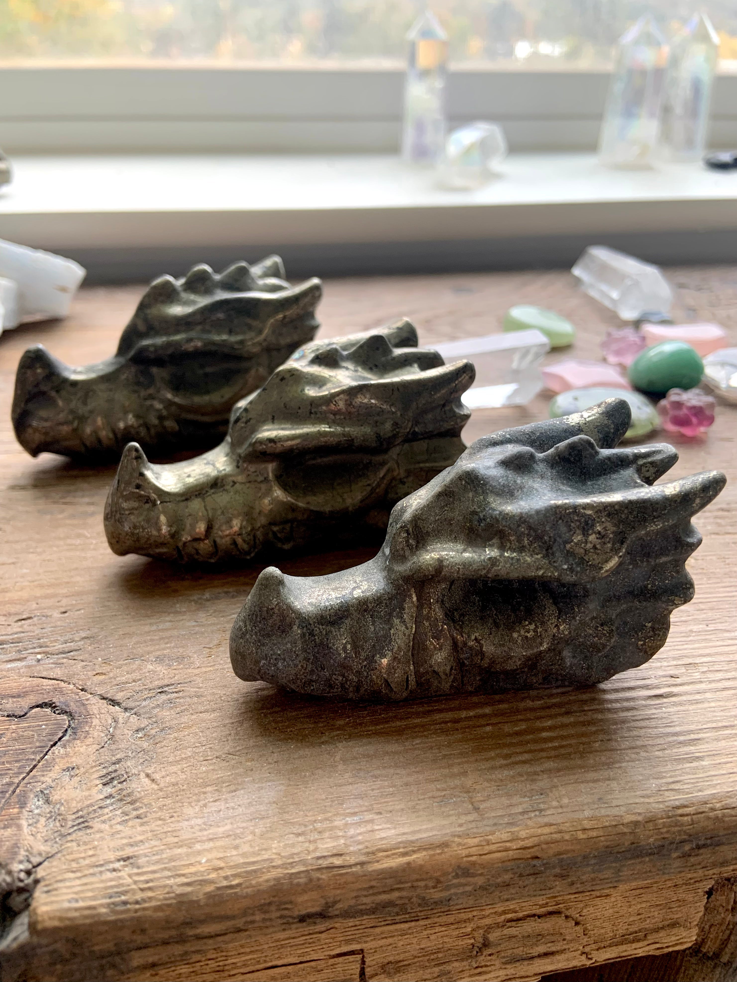 Pyrite crystal dragon carvings styled with clear quartz and rose quartz on wooden altar for energy protection