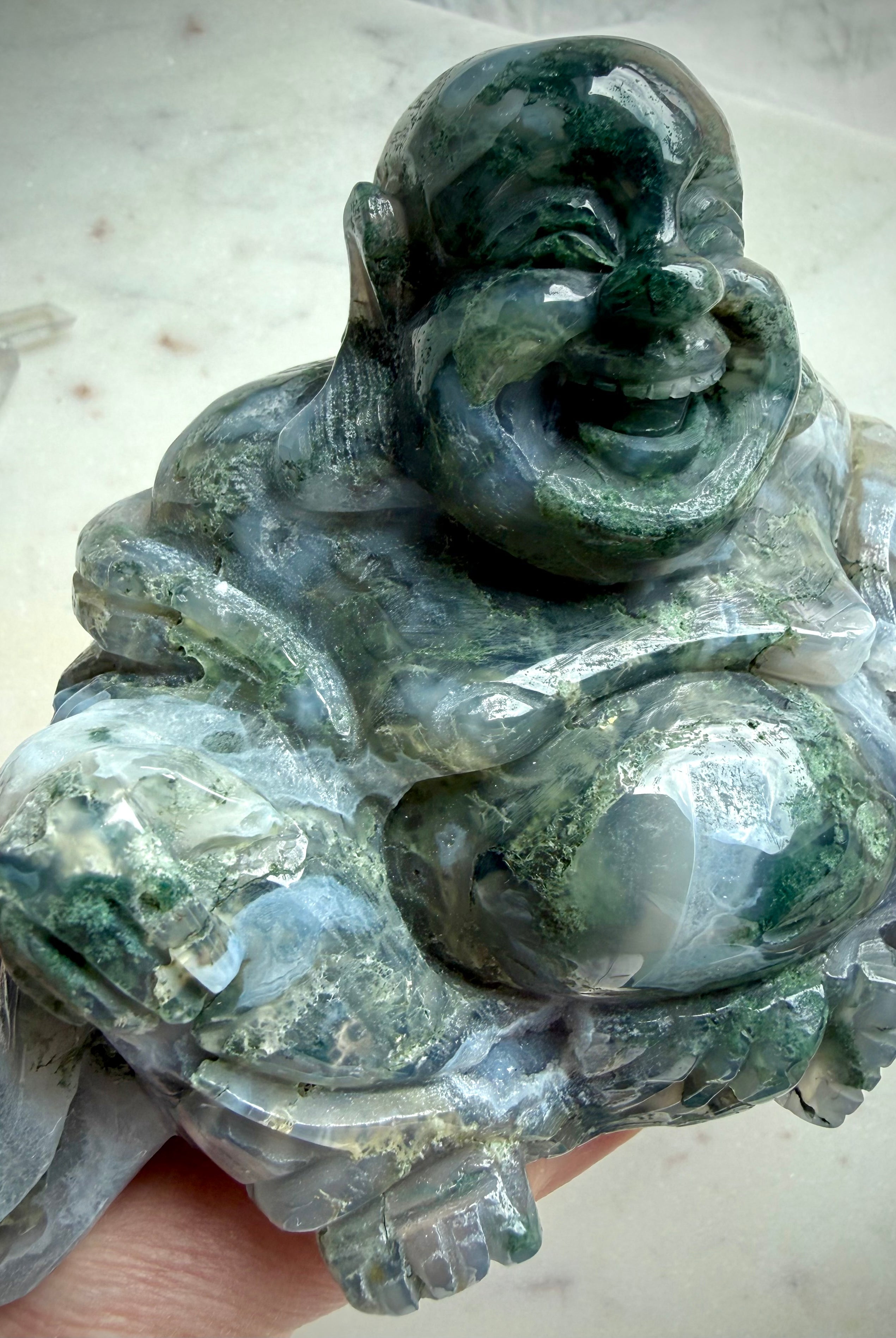 Three-quarter view of a Large Moss Agate Laughing Buddha crystal statue with polished finish