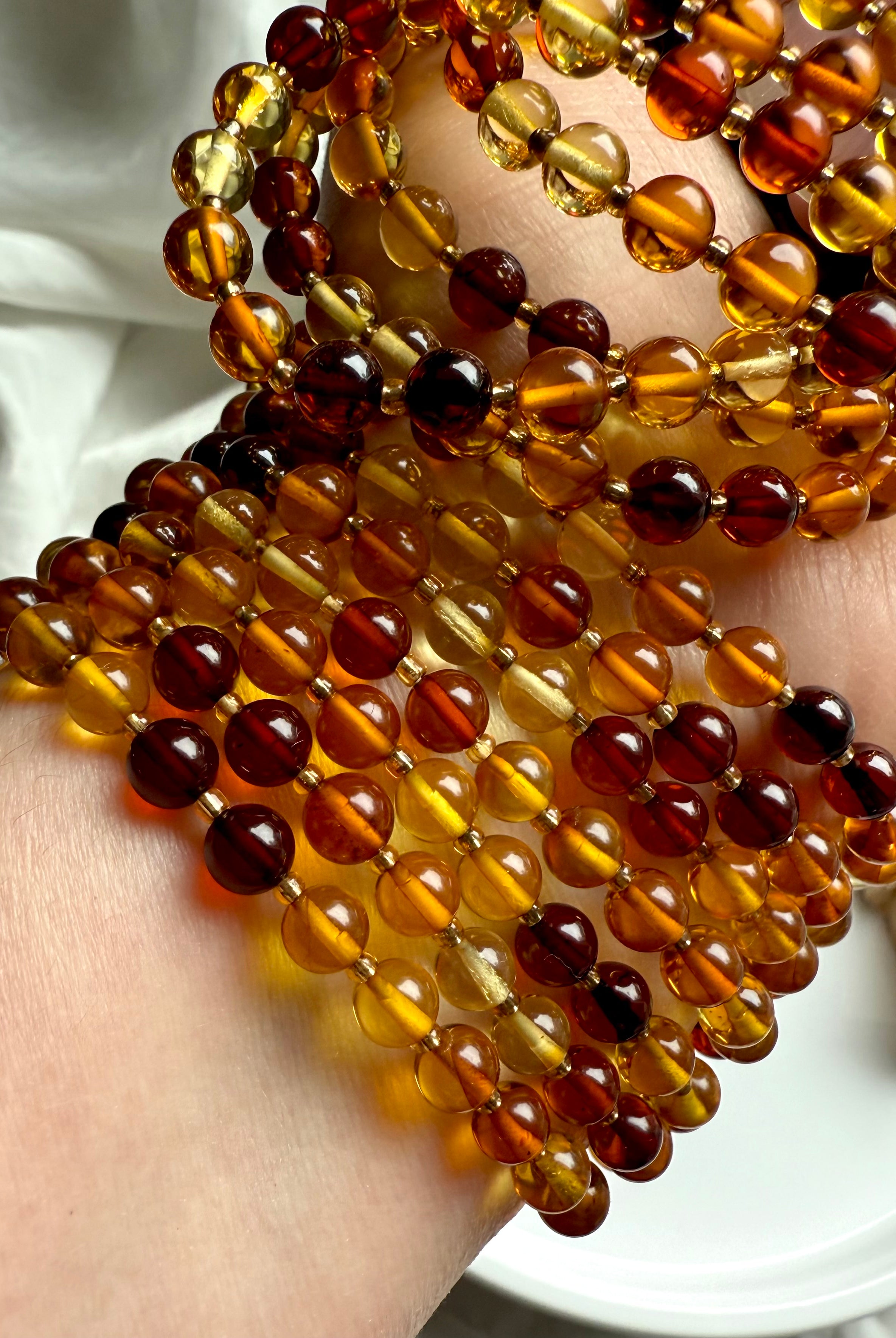 Layered amber beaded bracelets glowing with warmth + light – natural amber crystal for energy, confidence + joy