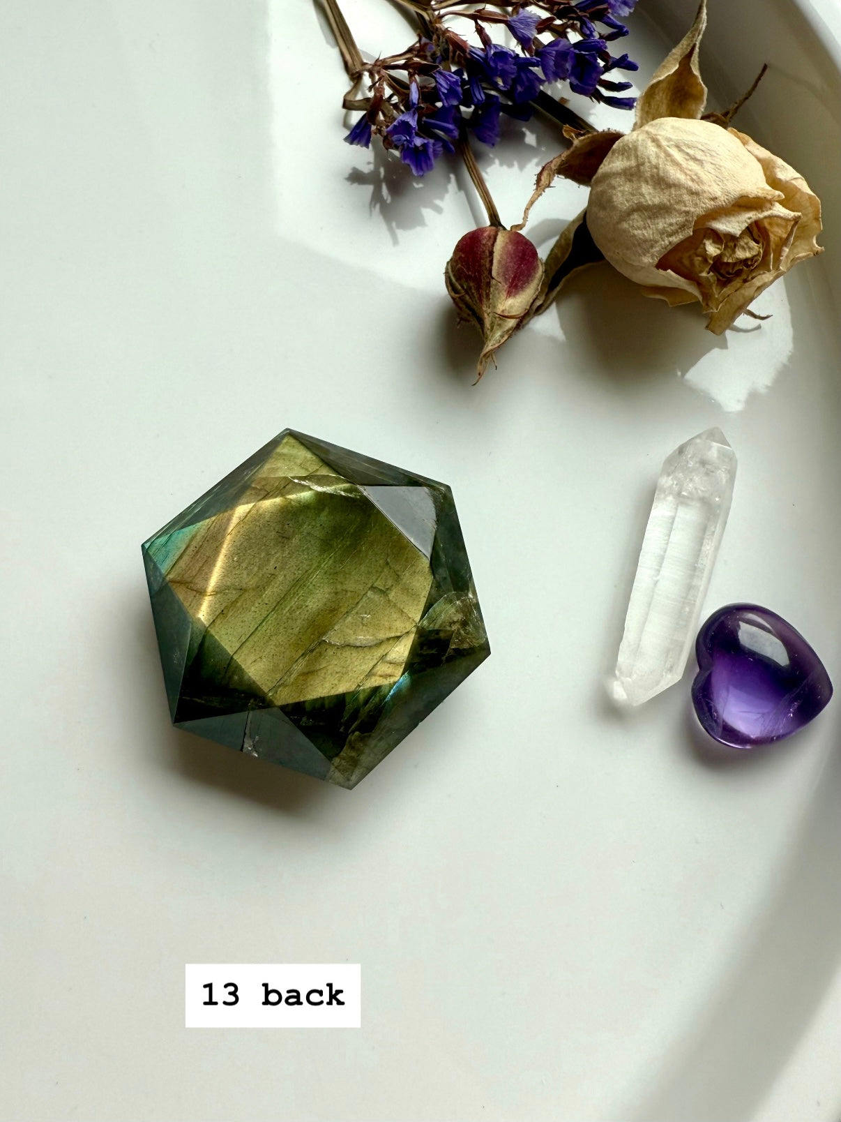 Crystal flatlay featuring faceted Labradorite hexagon with sacred geometry arrangement of quartz and flowers