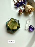 Crystal flatlay featuring faceted Labradorite hexagon with sacred geometry arrangement of quartz and flowers