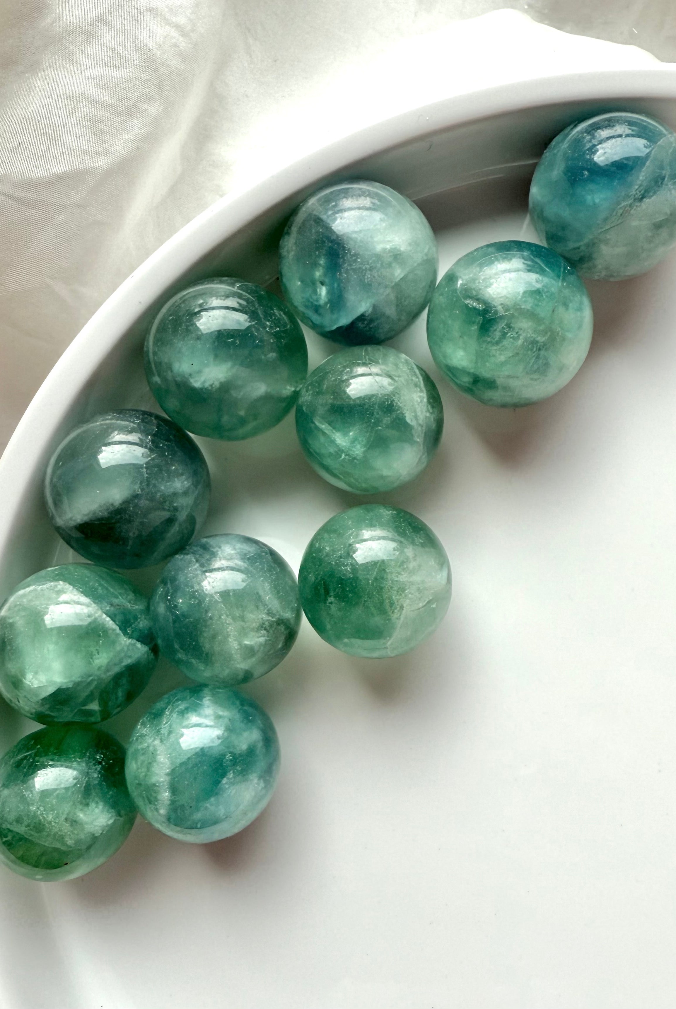 Group of mini teal Fluorite spheres with shimmering aqua tones, polished healing crystals for meditation and energy balance.