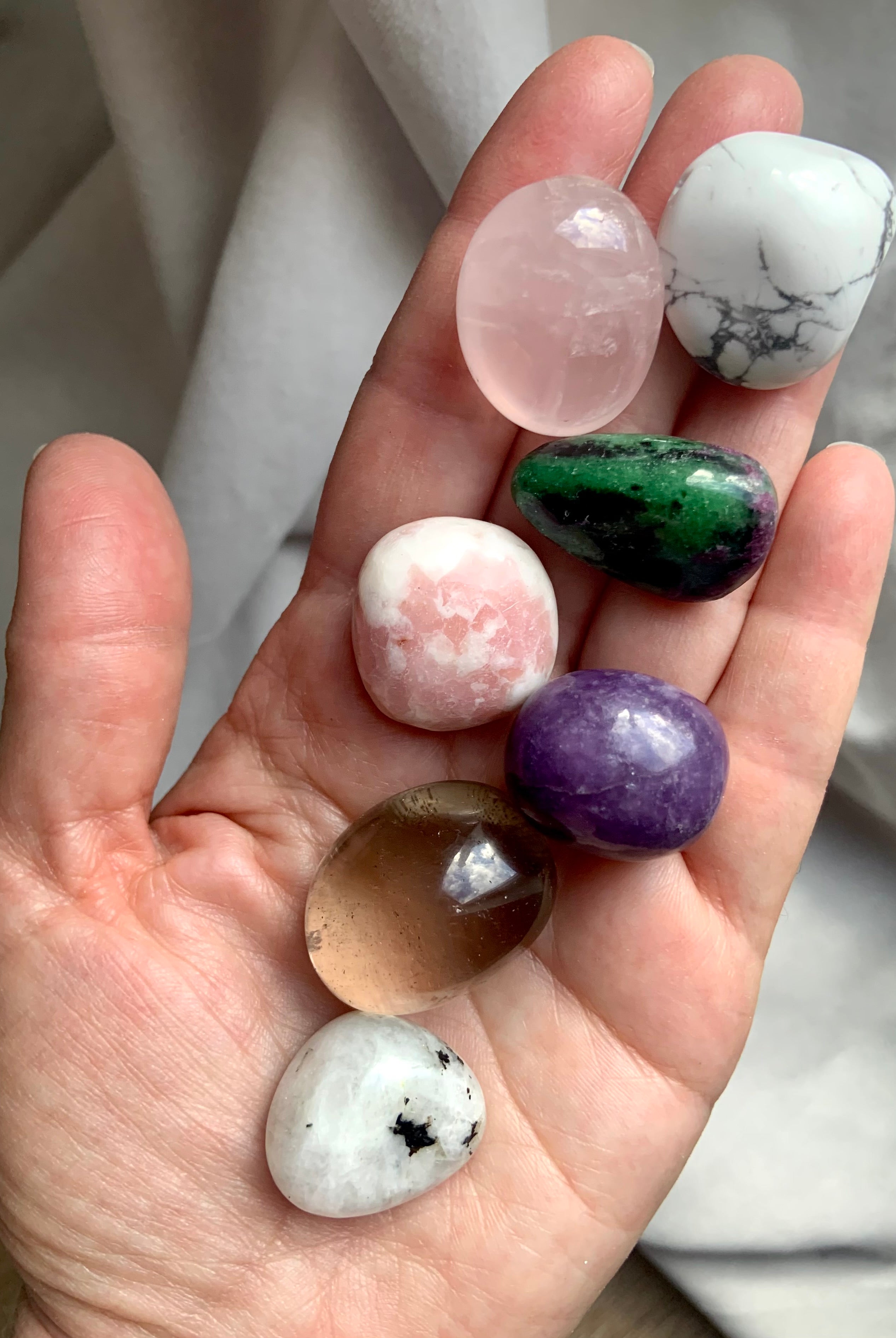 Grief support crystal set in my hand – includes rose quartz, smoky quartz, pink opal, moonstone, lepidolite, howlite & ruby zoisite