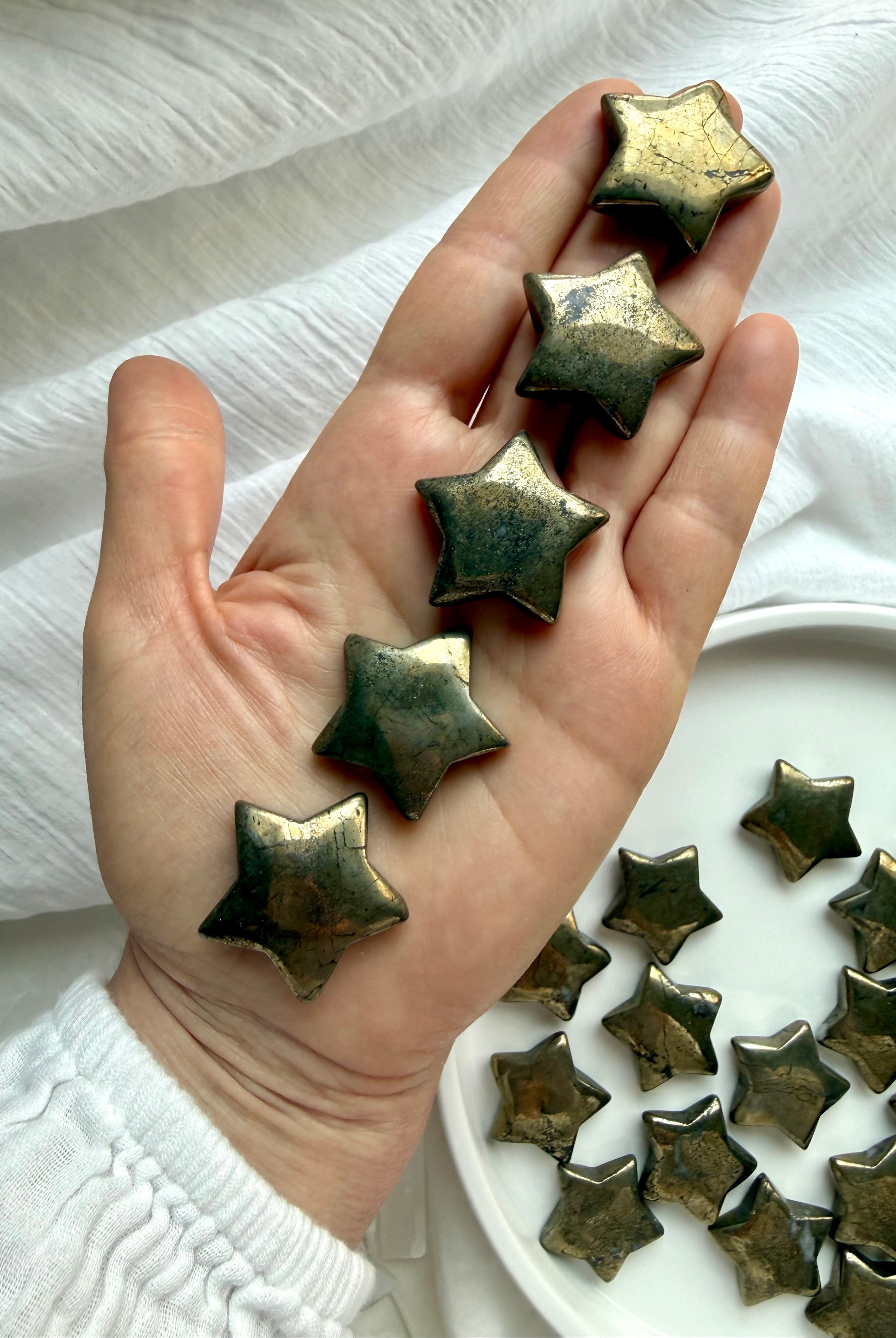 Pyrite stars held in hand showing natural golden metallic sheen and polished crystal finish