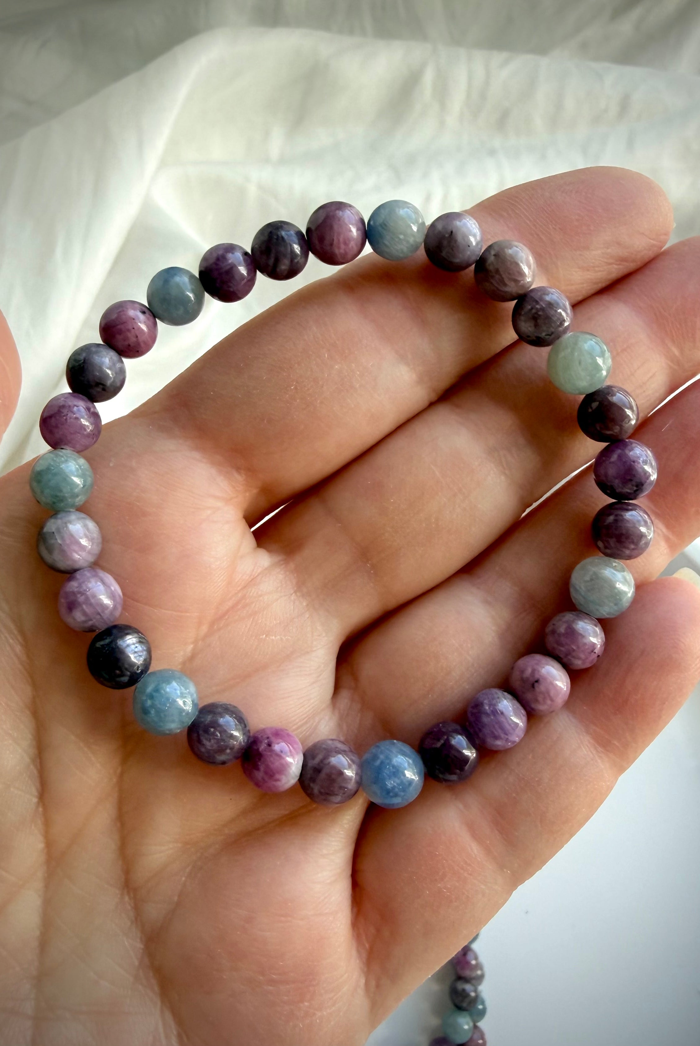 Ruby Sapphire crystal bracelet on hand showing the natural color variation of ruby & sapphire gemstone beads