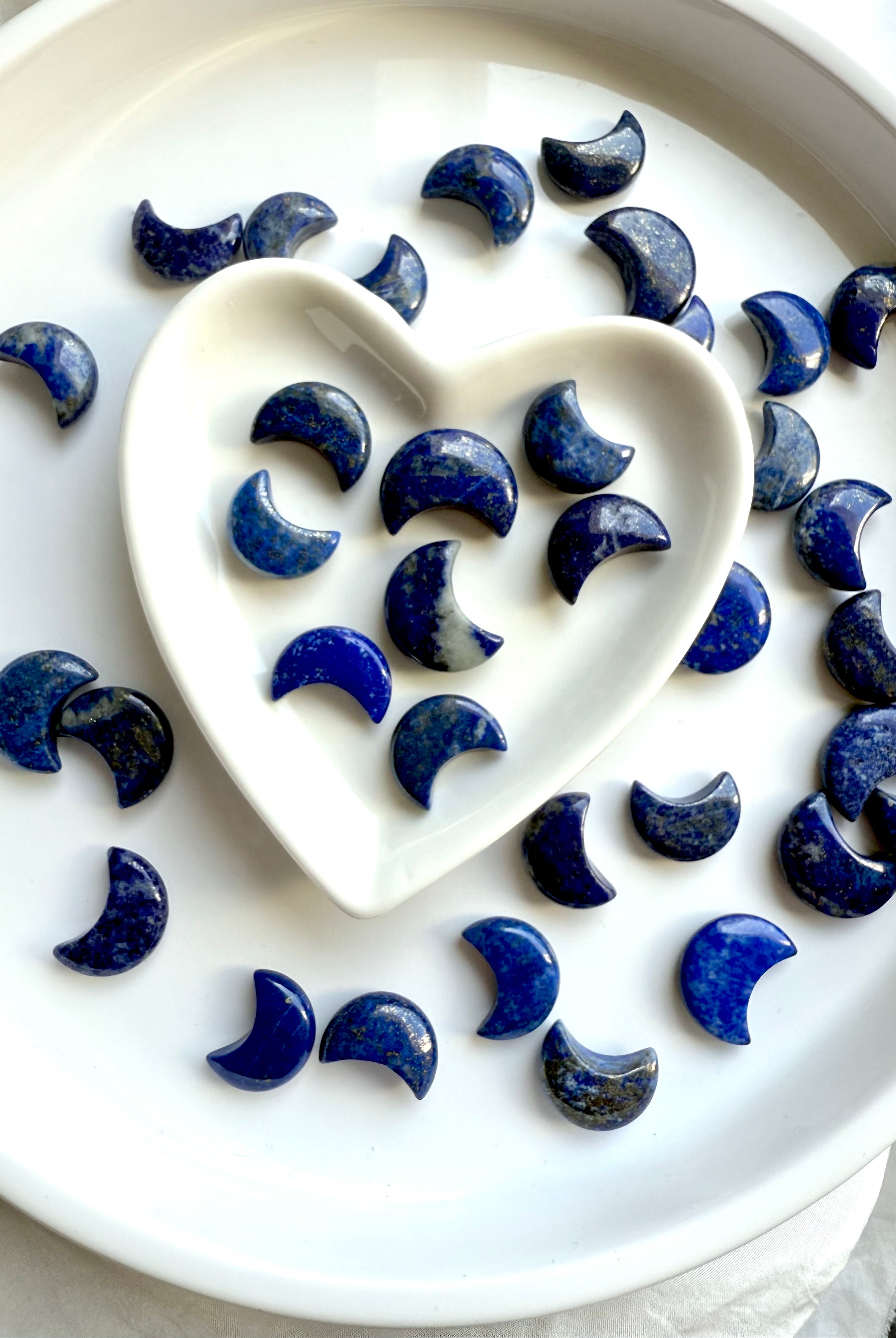 Lapis Lazuli mini moon carving – sacred crystal for wisdom and truth shown in a white heart bowl