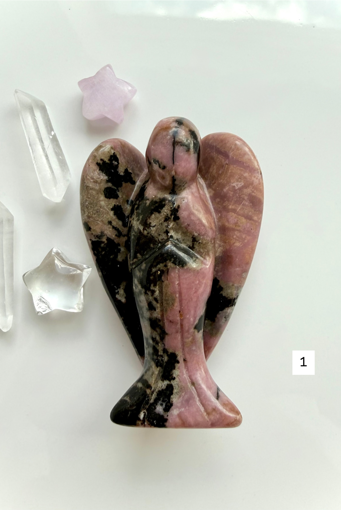 Rhodonite angel carving with soft pink tones and black matrix for heart healing and compassion