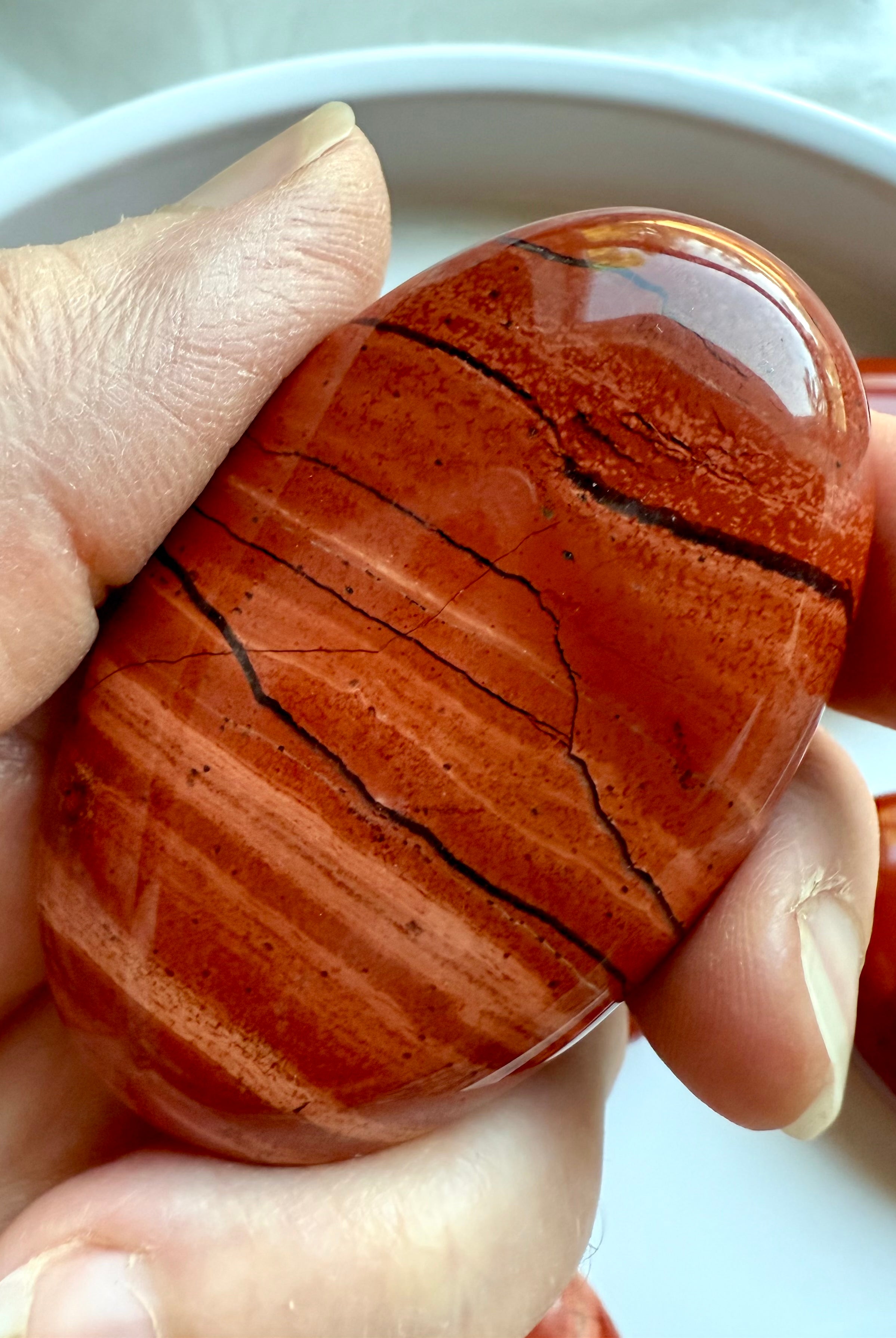 Macro shot of Red Jasper palm stone — grounding stone with rich red color and stabilizing energy.