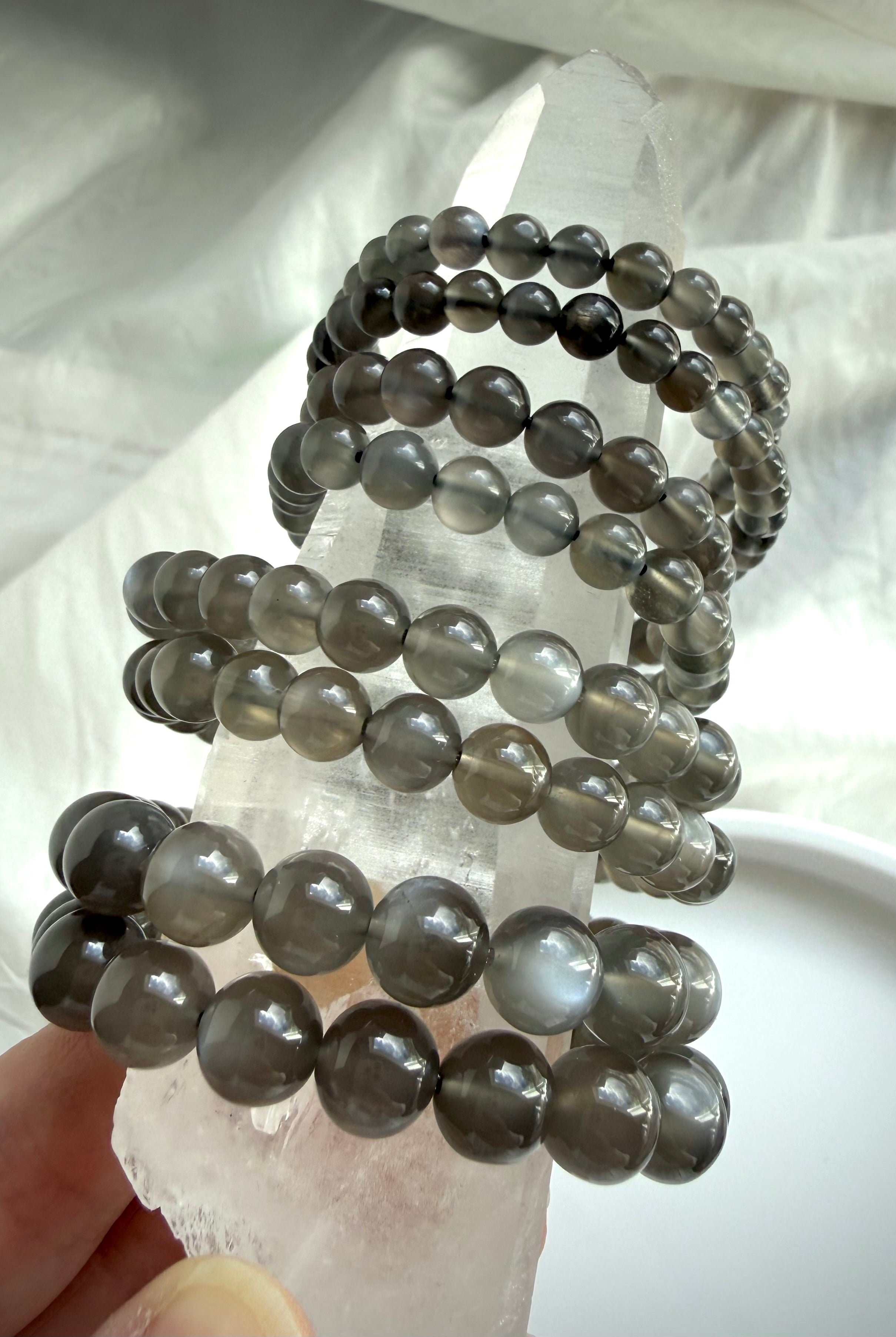 Black Moonstone bracelets displayed on Clear Quartz with silky adularescence and translucent inky charcoal gemstone beads
