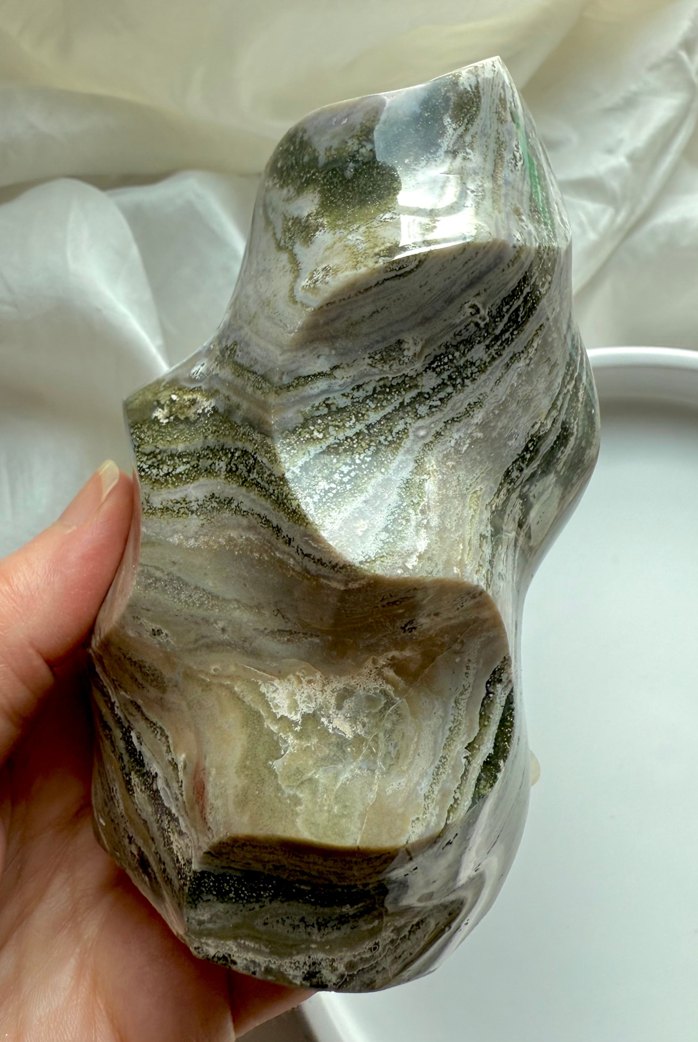 Side view of Green Ocean Jasper flame showing layered forest-green and cream patterns in a smooth freeform sculpture.