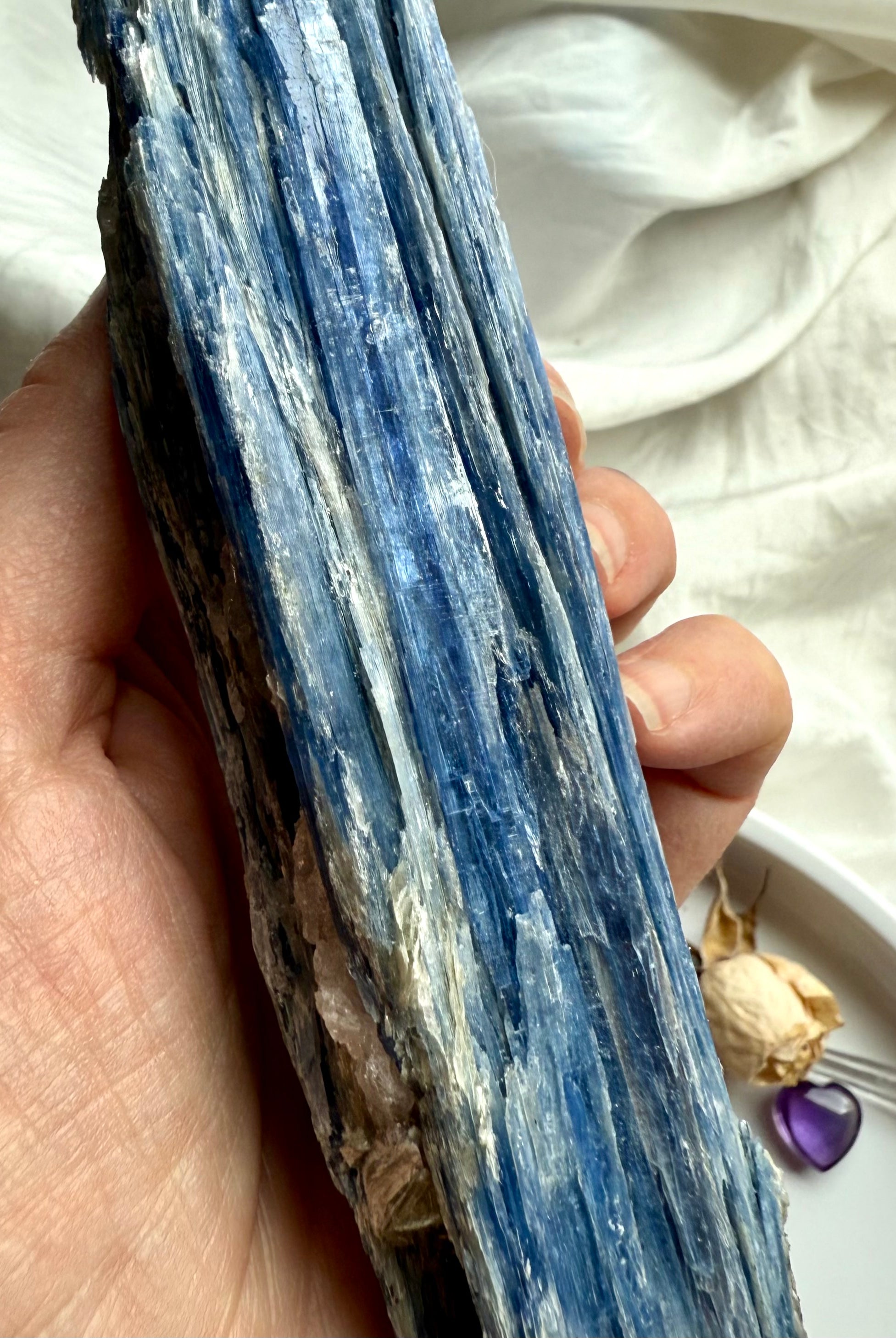 Macro close-up of blue kyanite crystal blades with quartz seam, shimmering muscovite + subtle black tourmaline inclusions, raw healing gemstone texture