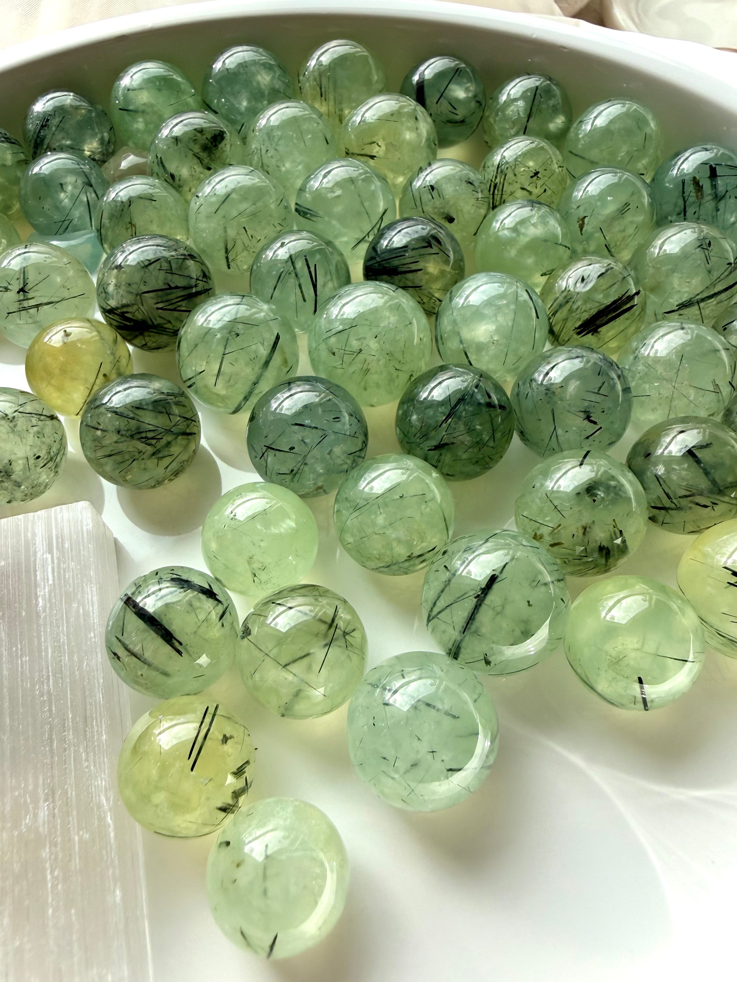 prehnite mini spheres arranged on white surface with soft green color and natural internal patterns