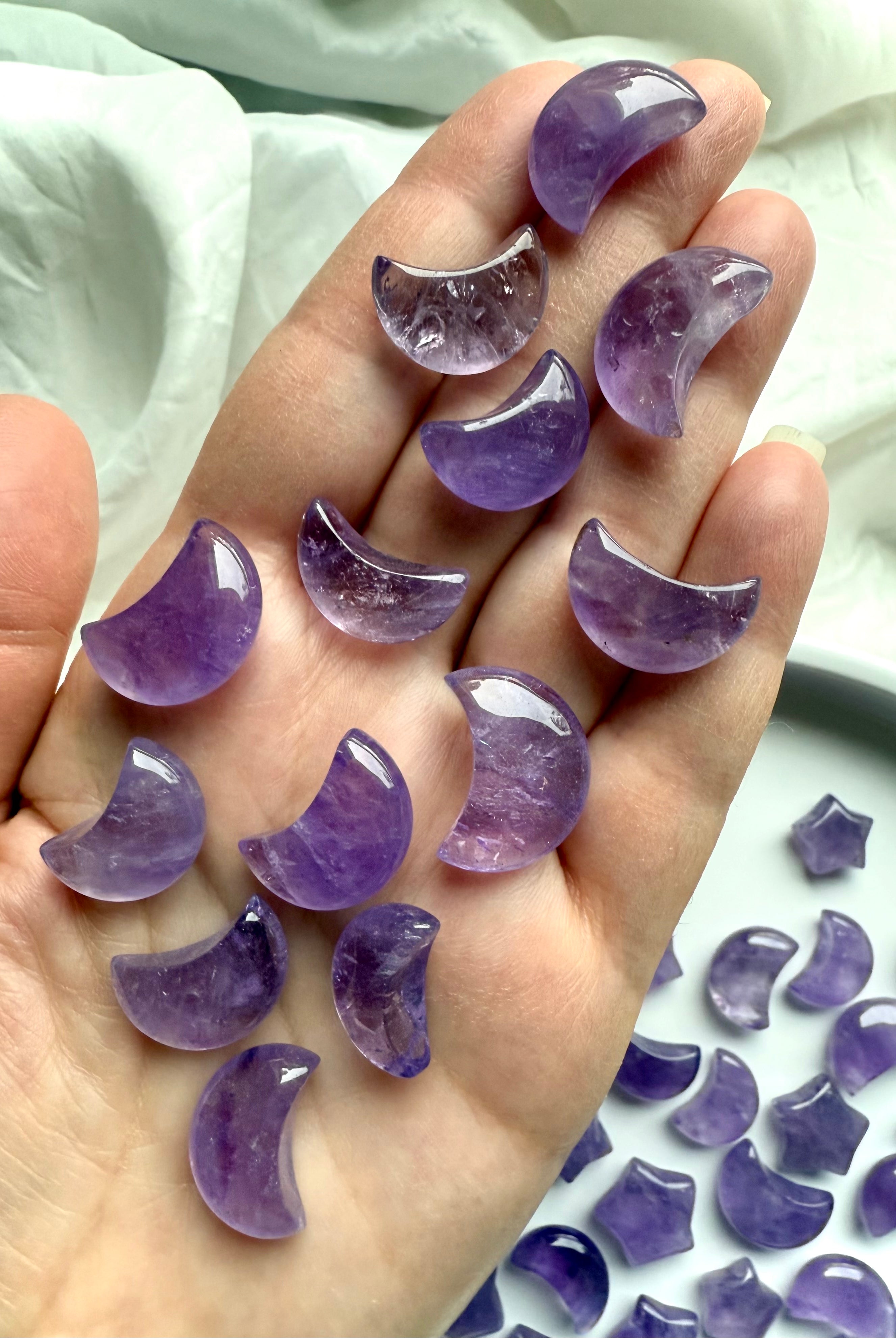 Hand holding small amethyst crescent moons showing size and smooth polish
