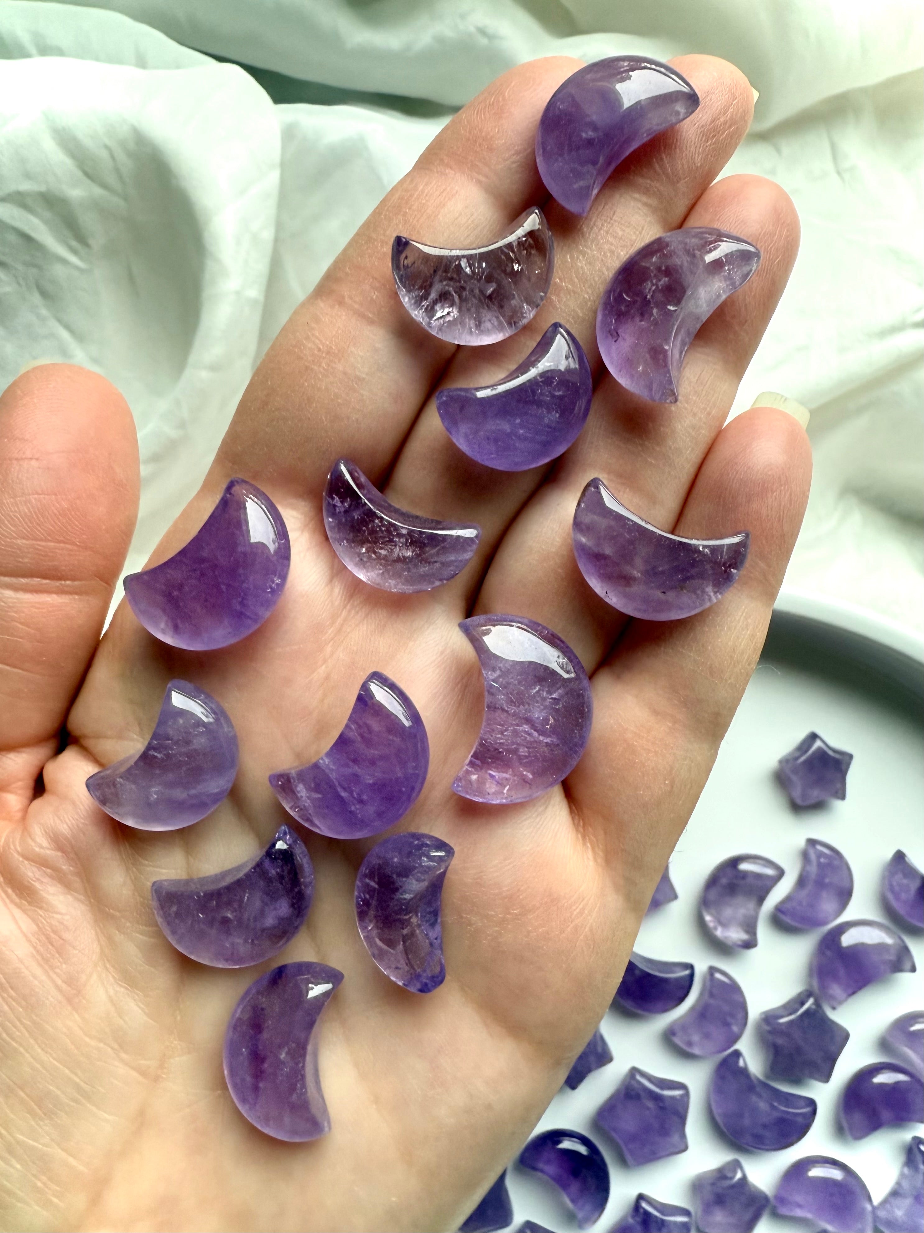 Hand holding small amethyst crescent moons showing size and smooth polish