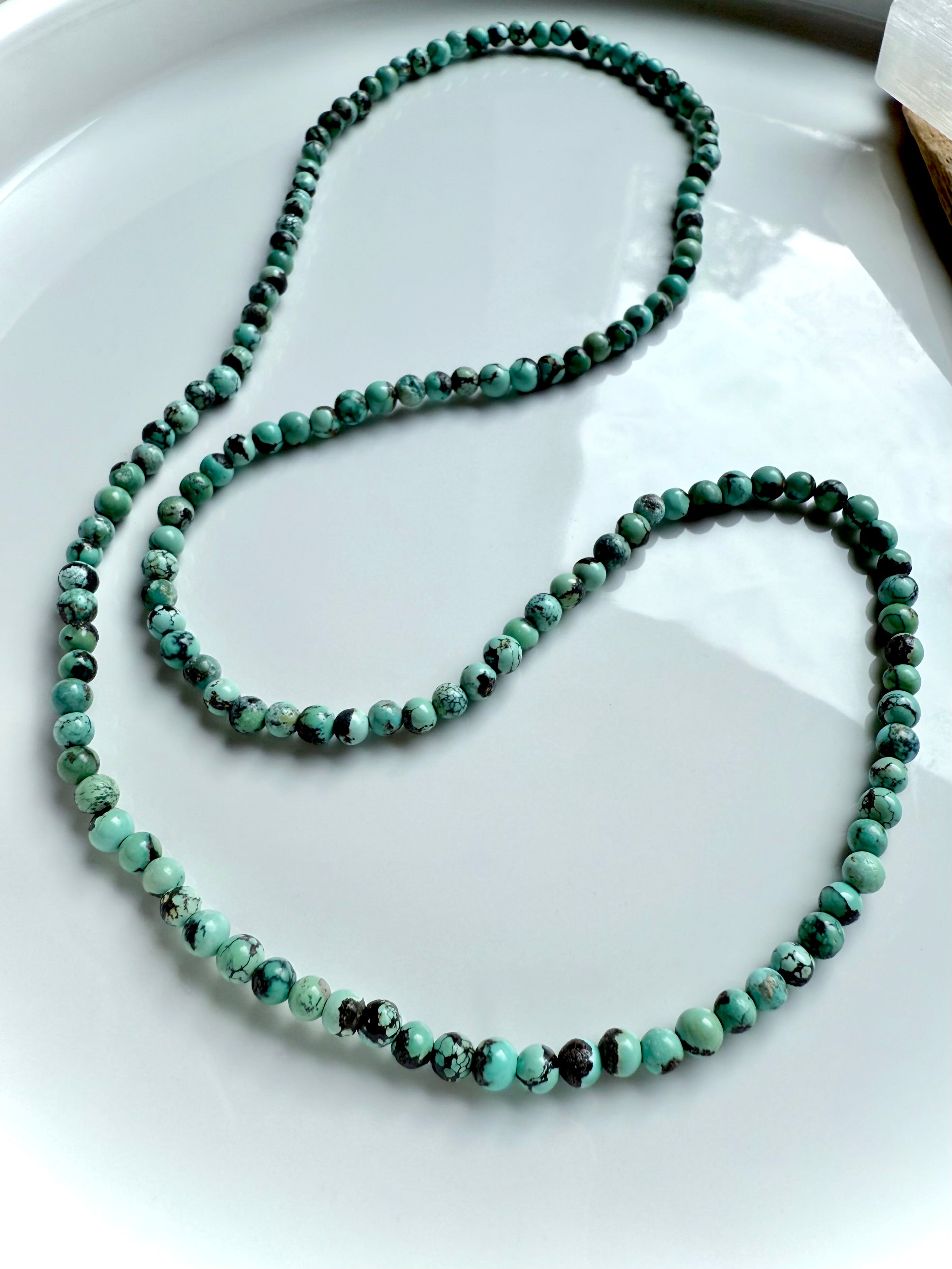 Turquoise necklace variation displayed in an elegant loop with smooth, natural gemstone beads in blue-green tones