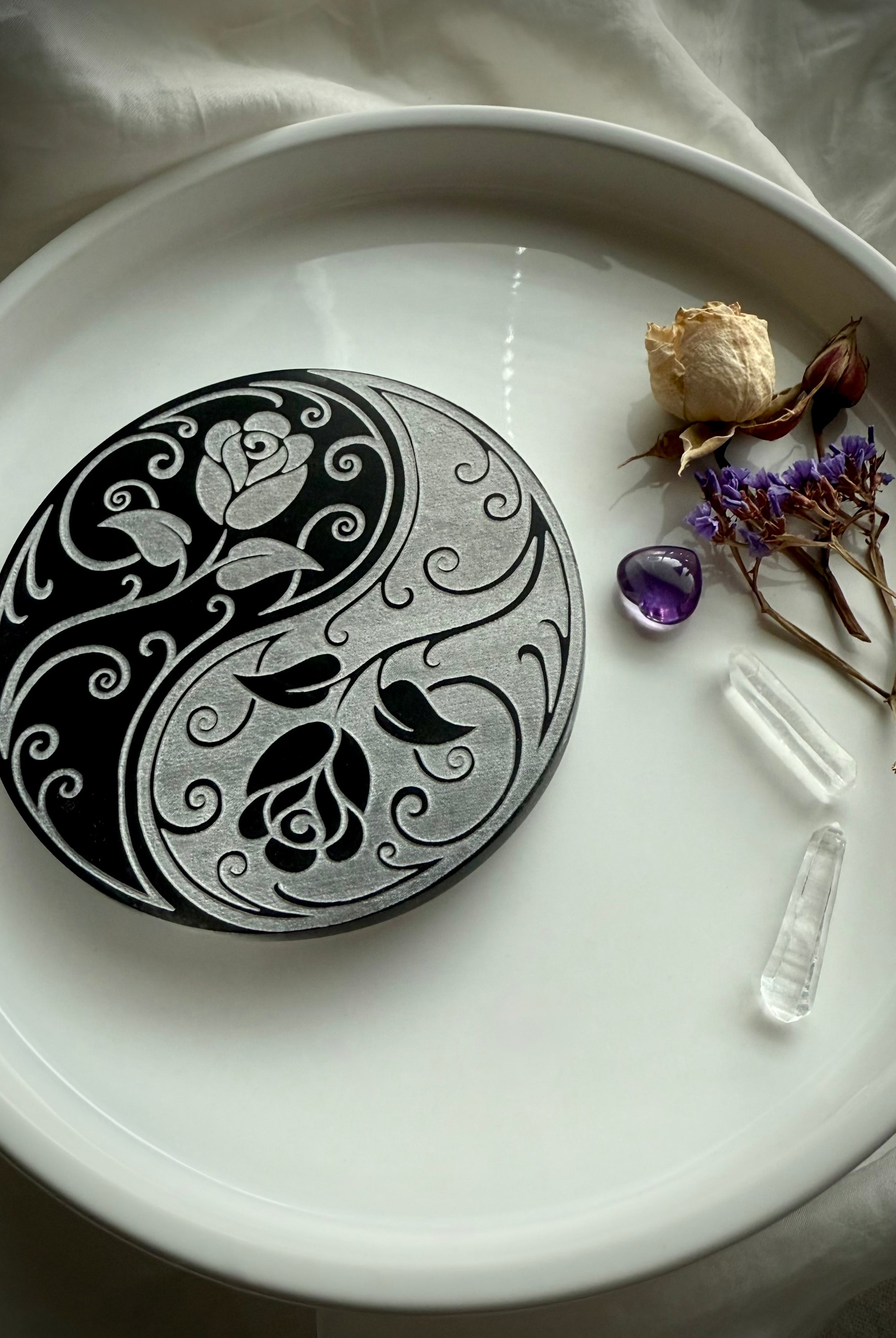 Round selenite charging plate with yin yang rose design styled with crystals and flowers for cleansing rituals