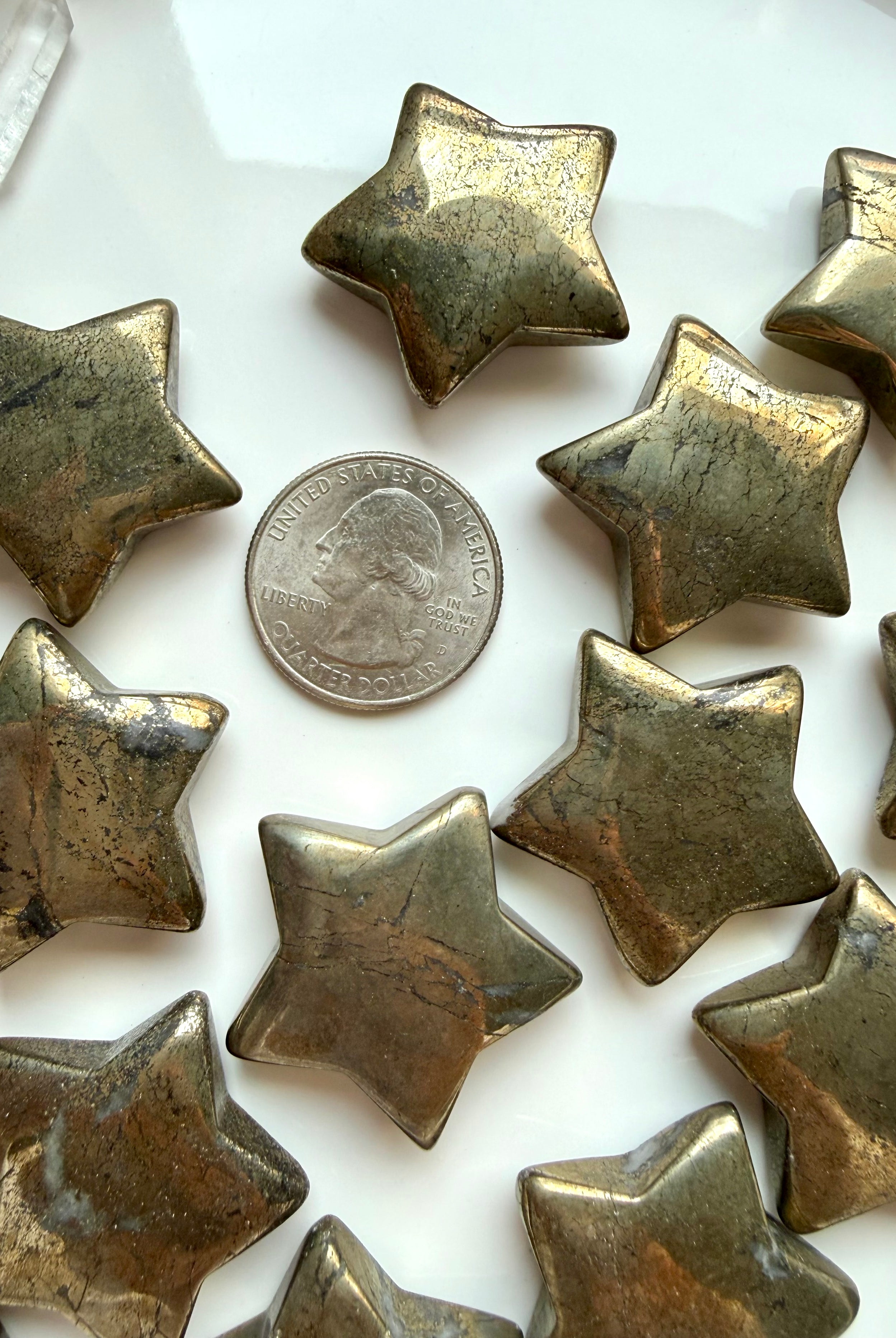 Pyrite star crystals shown with a US quarter for scale, with reflective gold surface & natural patterns
