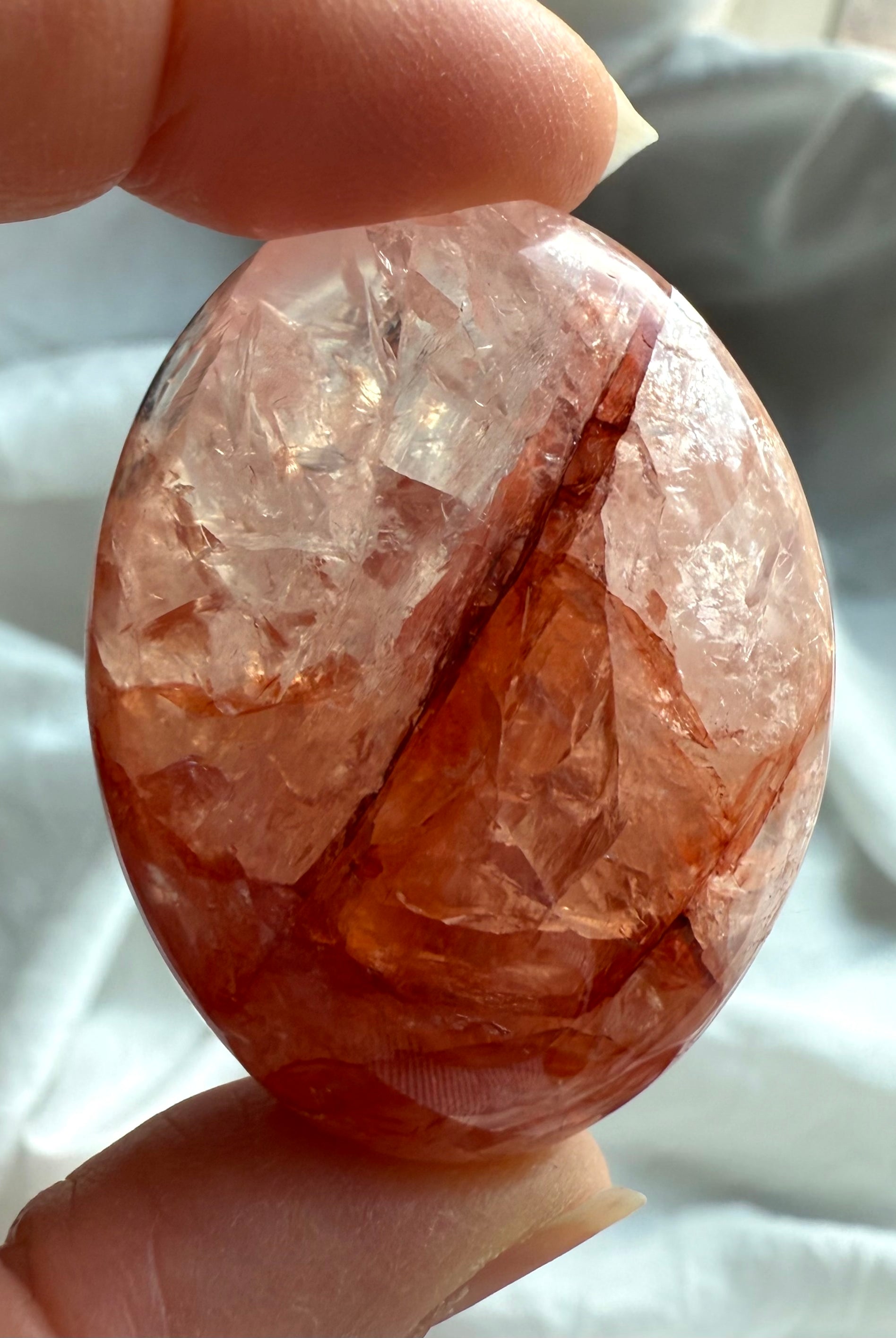 Closeup of Fire Quartz palm stone with fiery red inclusions and translucent quartz matrix