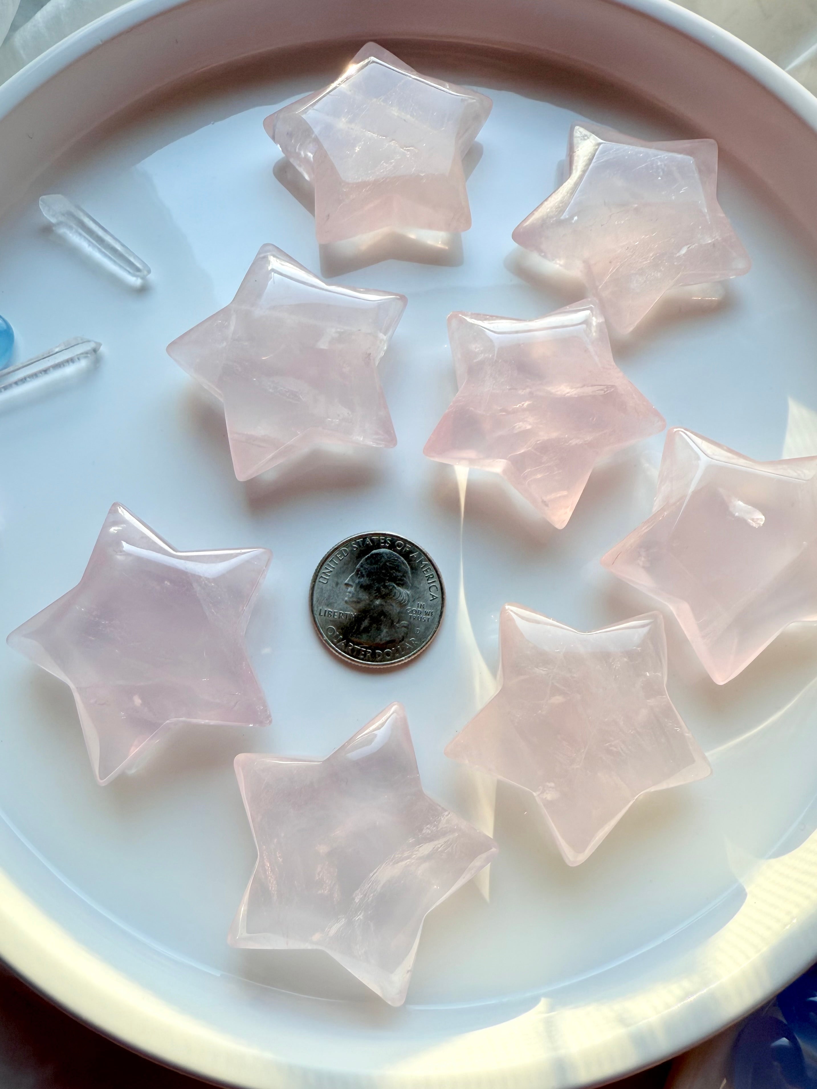 Group of large Mozambique Rose Quartz Stars with a US quarter for scale— hand-carved pink crystal star shapes for love, harmony, and sacred space décor.