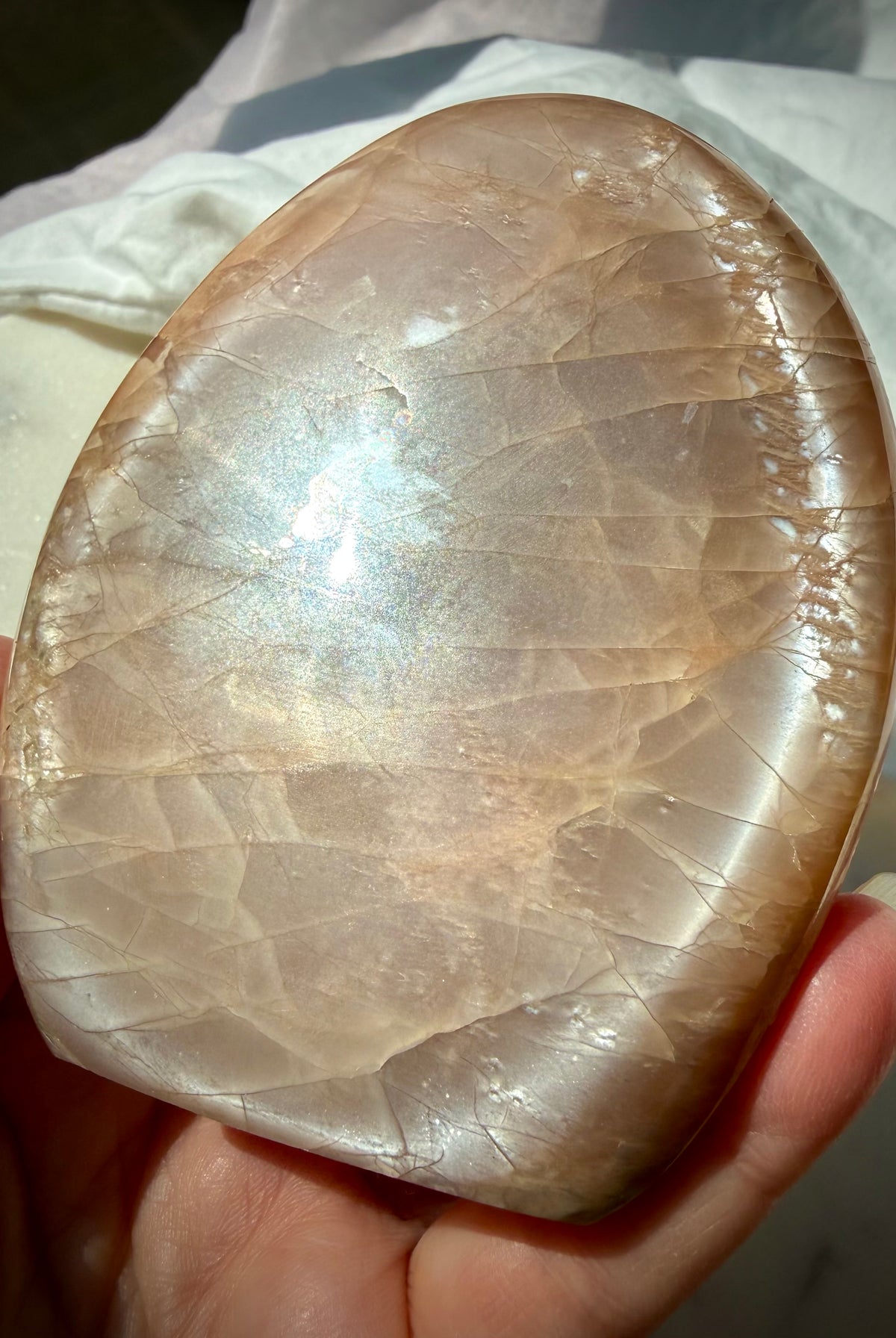 Peach Moonstone crystal showing silvery glow, golden Sunstone sparkle and natural rainbow reflections in angled light
