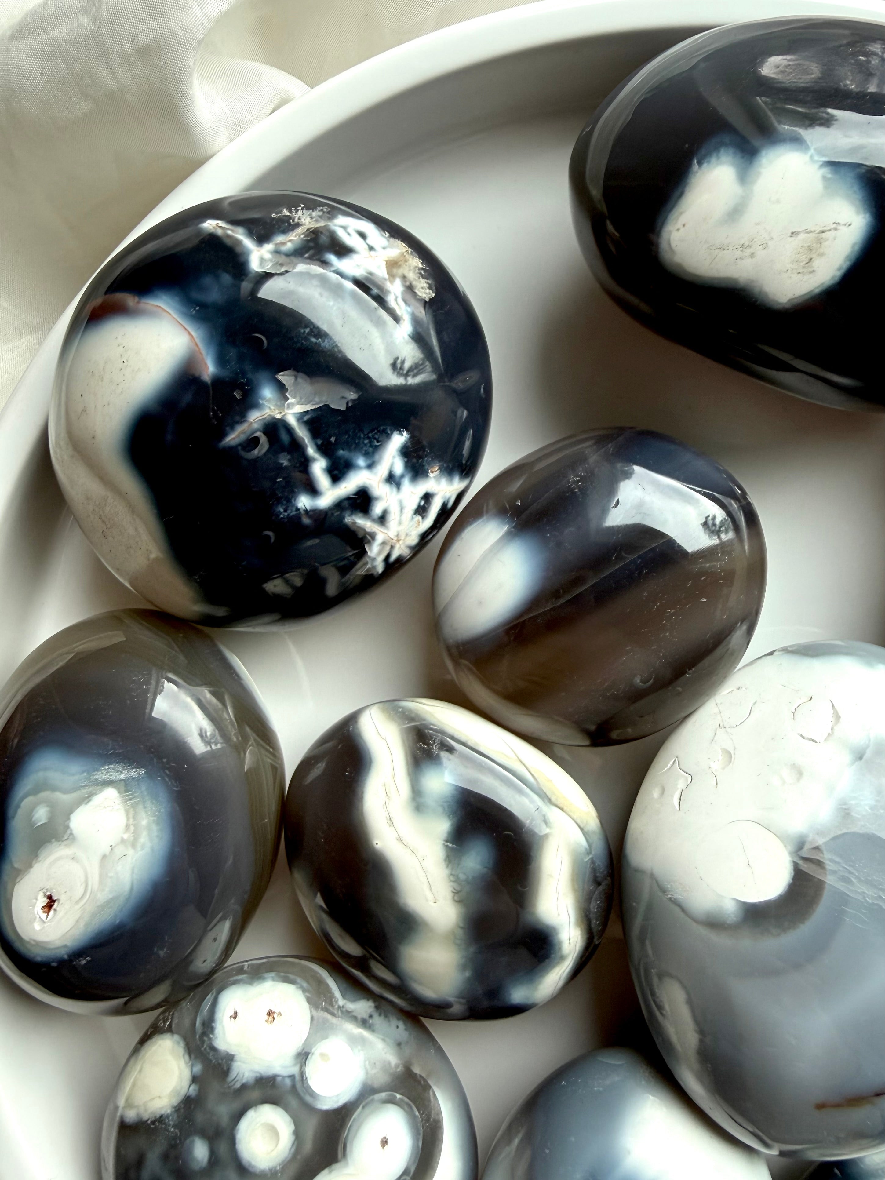 Detailed view of polished Orca Agate stones, highlighting organic banding and tranquil patterns associated with emotional healing