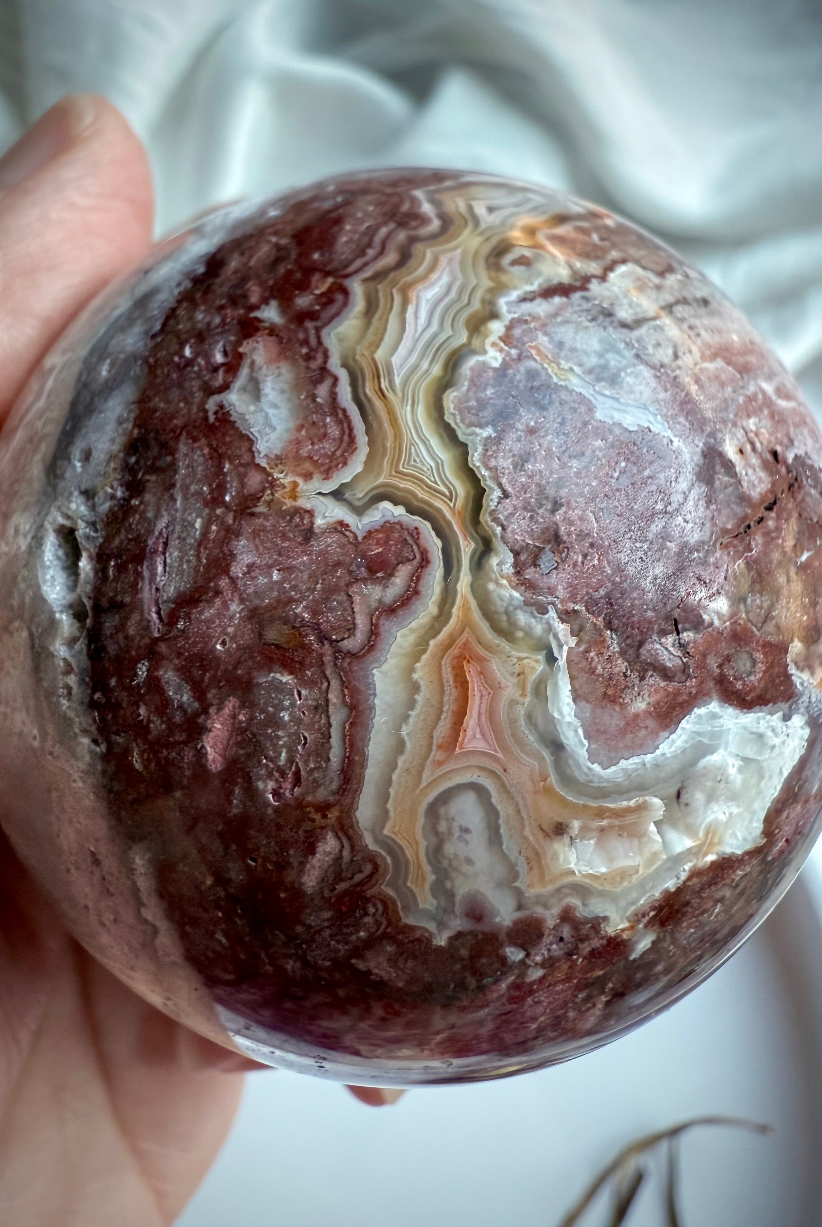 Textured agate sphere showing layered natural banding, soft mauve tones, and druzy cave formation
