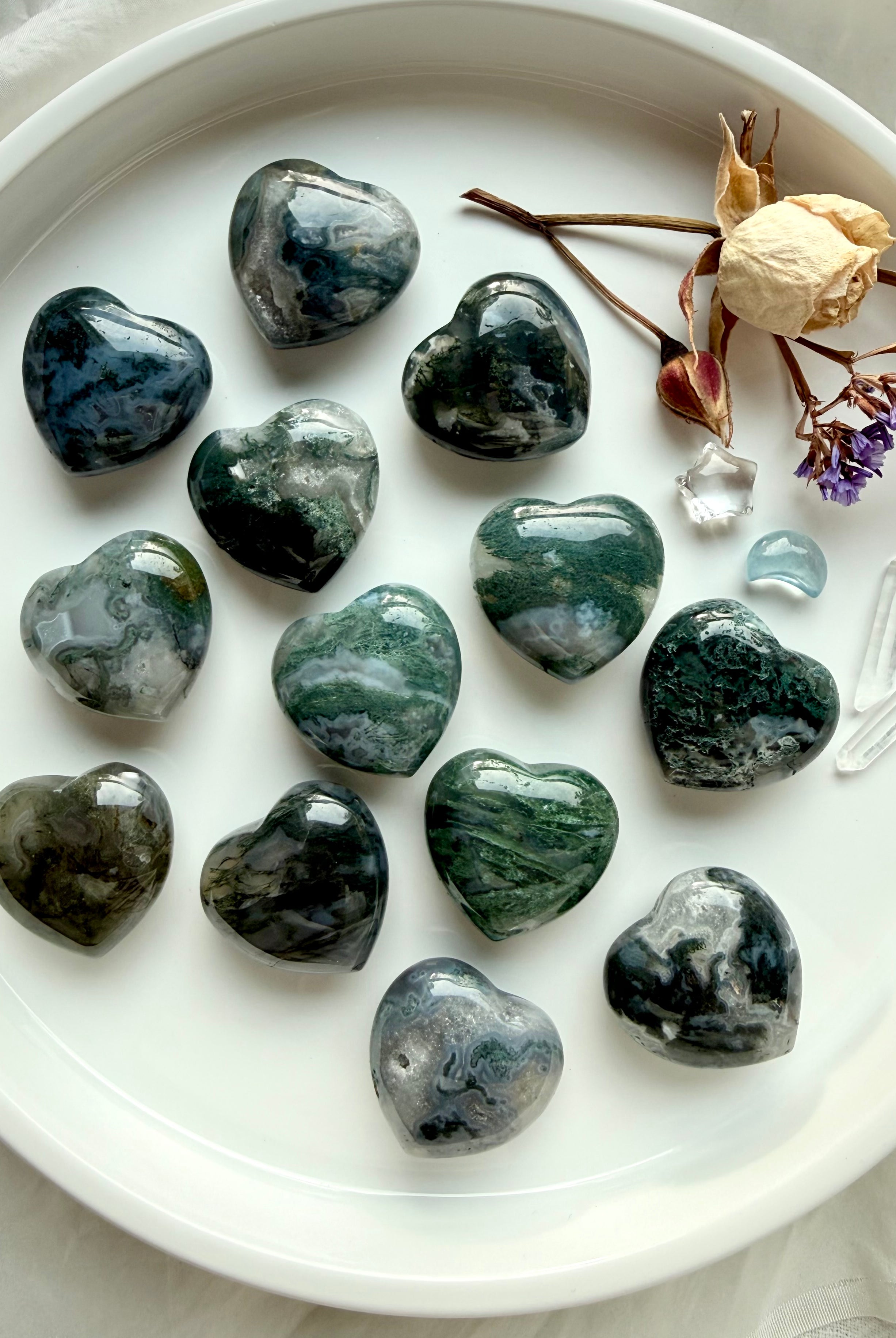 Moss Agate hearts with forest-green moss patterns and translucent quartz, arranged on a white tray