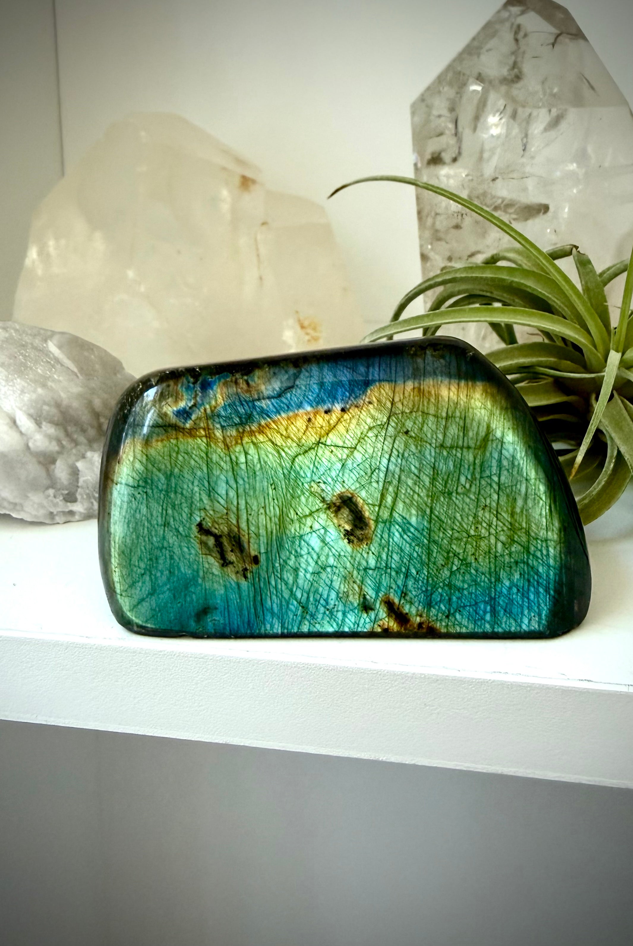 Polished Labradorite freeform with blue green flash displayed in home decor with crystals