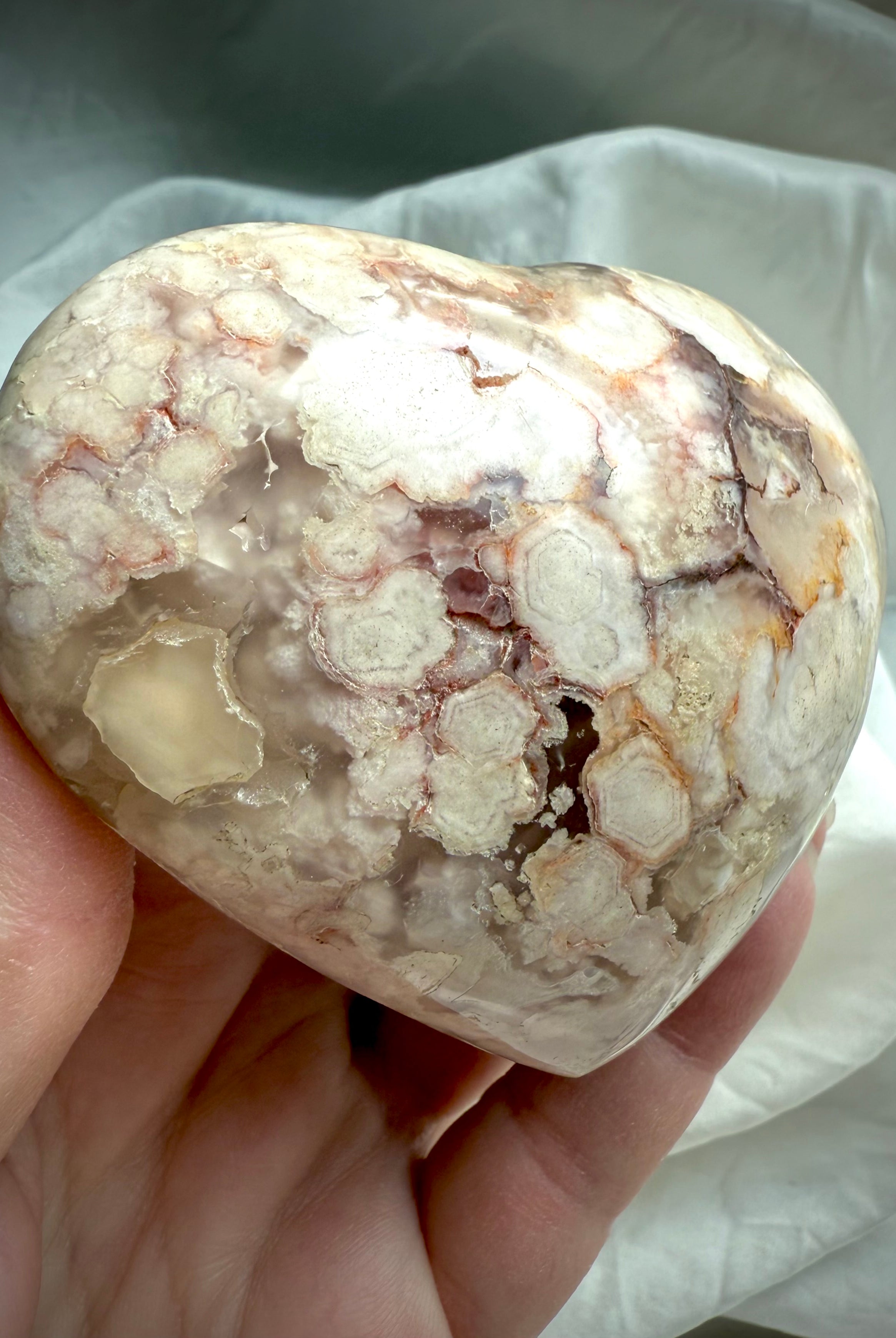Detailed view of a Flower Agate heart with clustered blossom formations and creamy chalcedony swirls — soothing stone for self-love, renewal, and emotional resilience.